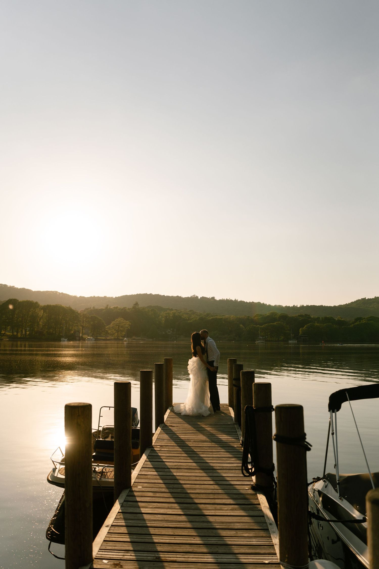Wooden dock extending into a peaceful lake at golden hour.