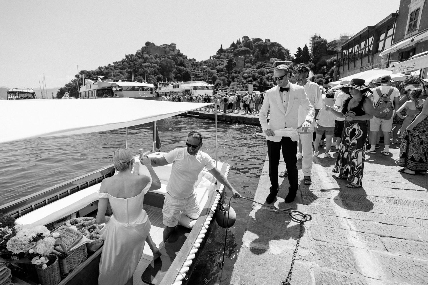 Wedding couple boarding a boat at an Italian lakeside dock in black and white photography.