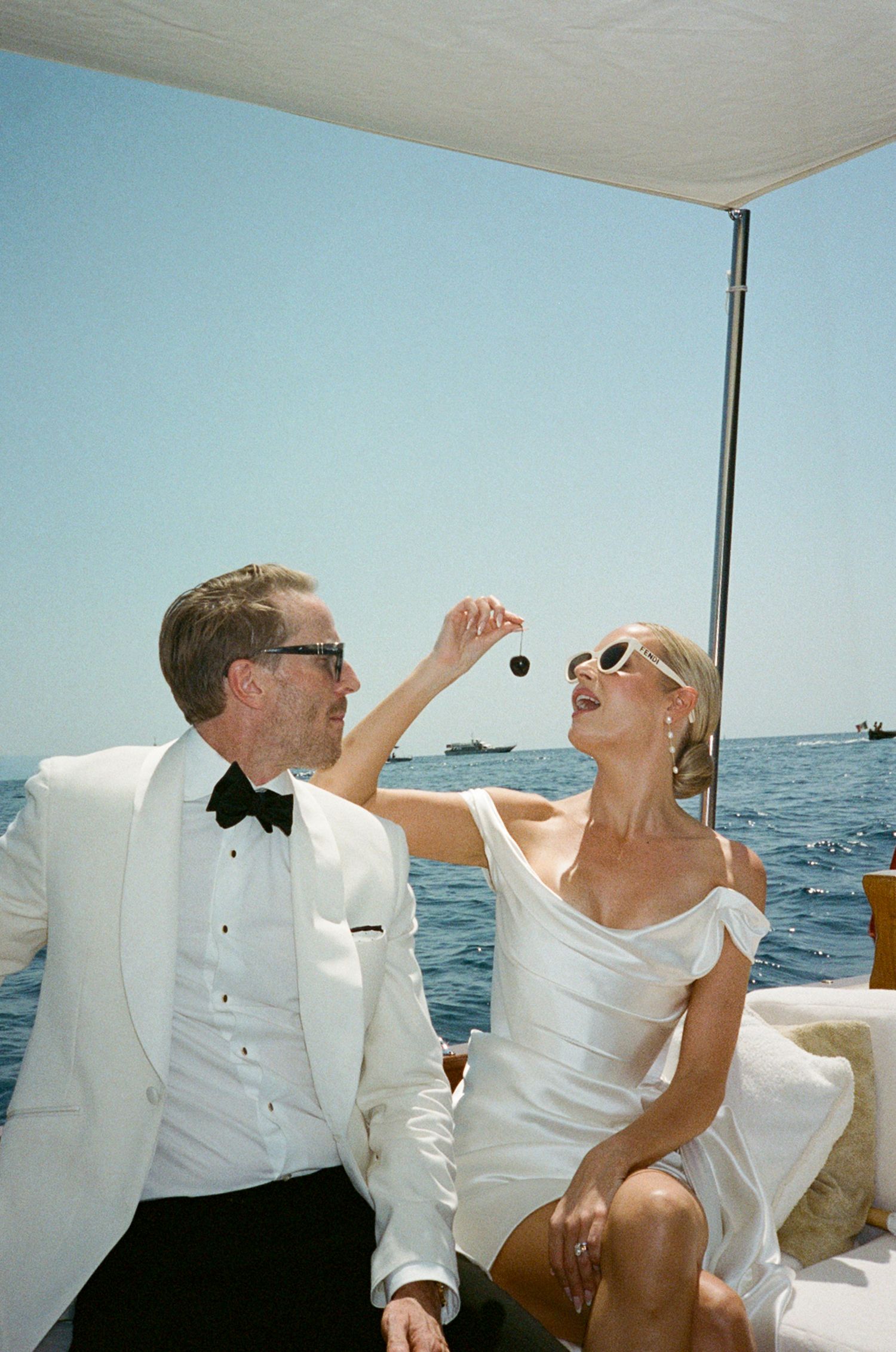 Couple in wedding attire sharing a playful moment on a luxury yacht with ocean views.