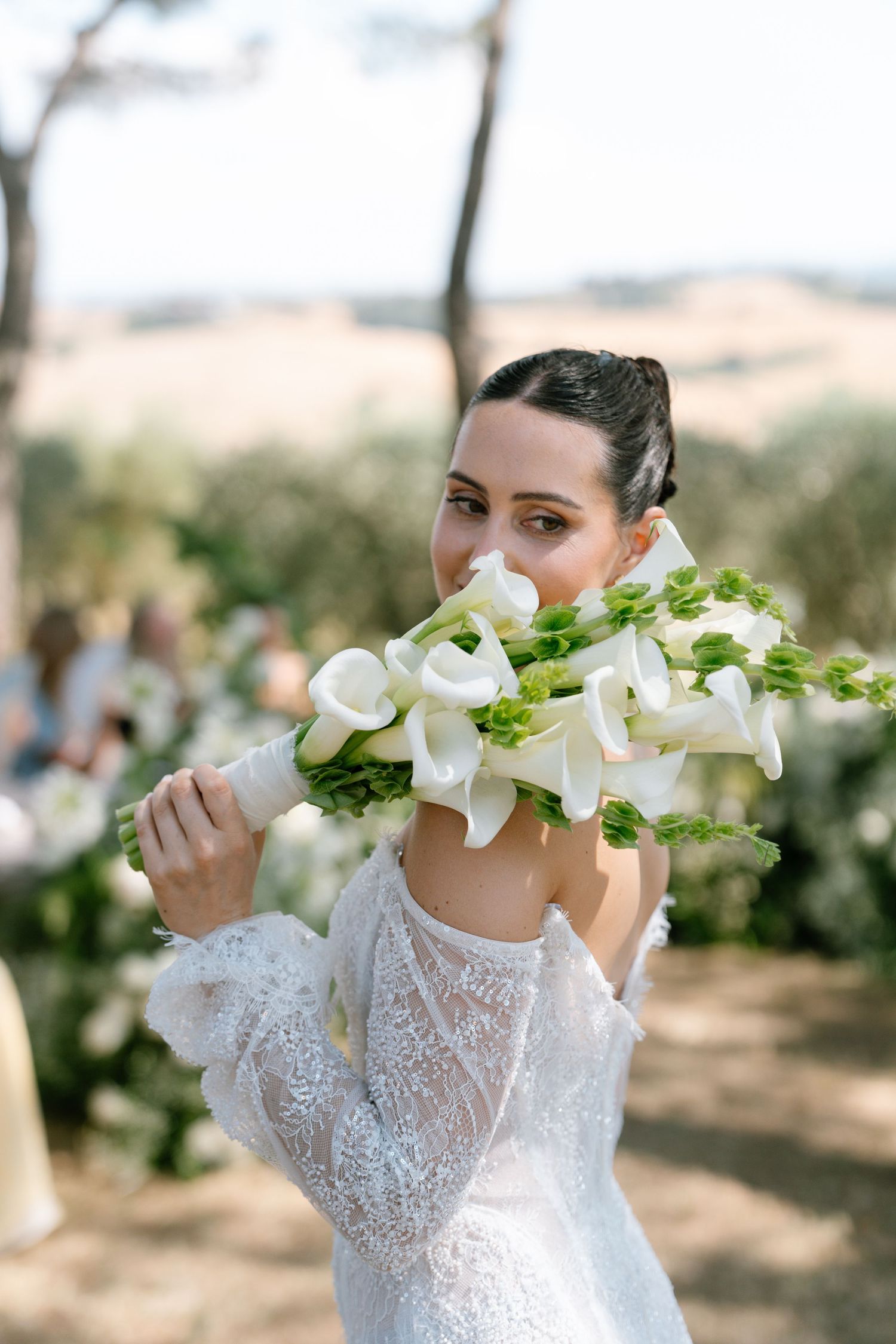 A bouquet of elegant white calla lilies being held in an outdoor setting.