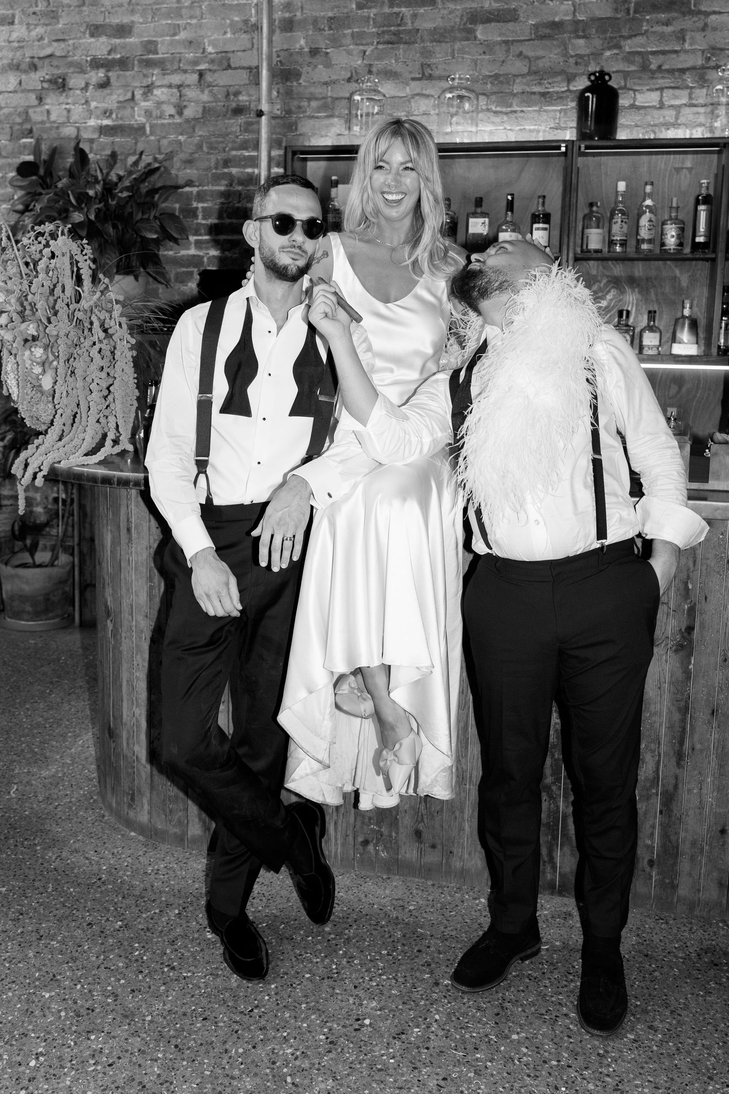 A celebratory moment captured in black and white at a rustic bar setting with brick walls.