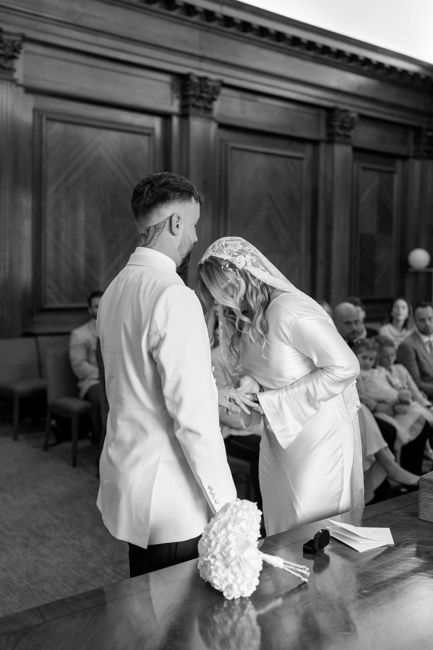 Black and white sequence of a couple signing documents at a formal event.