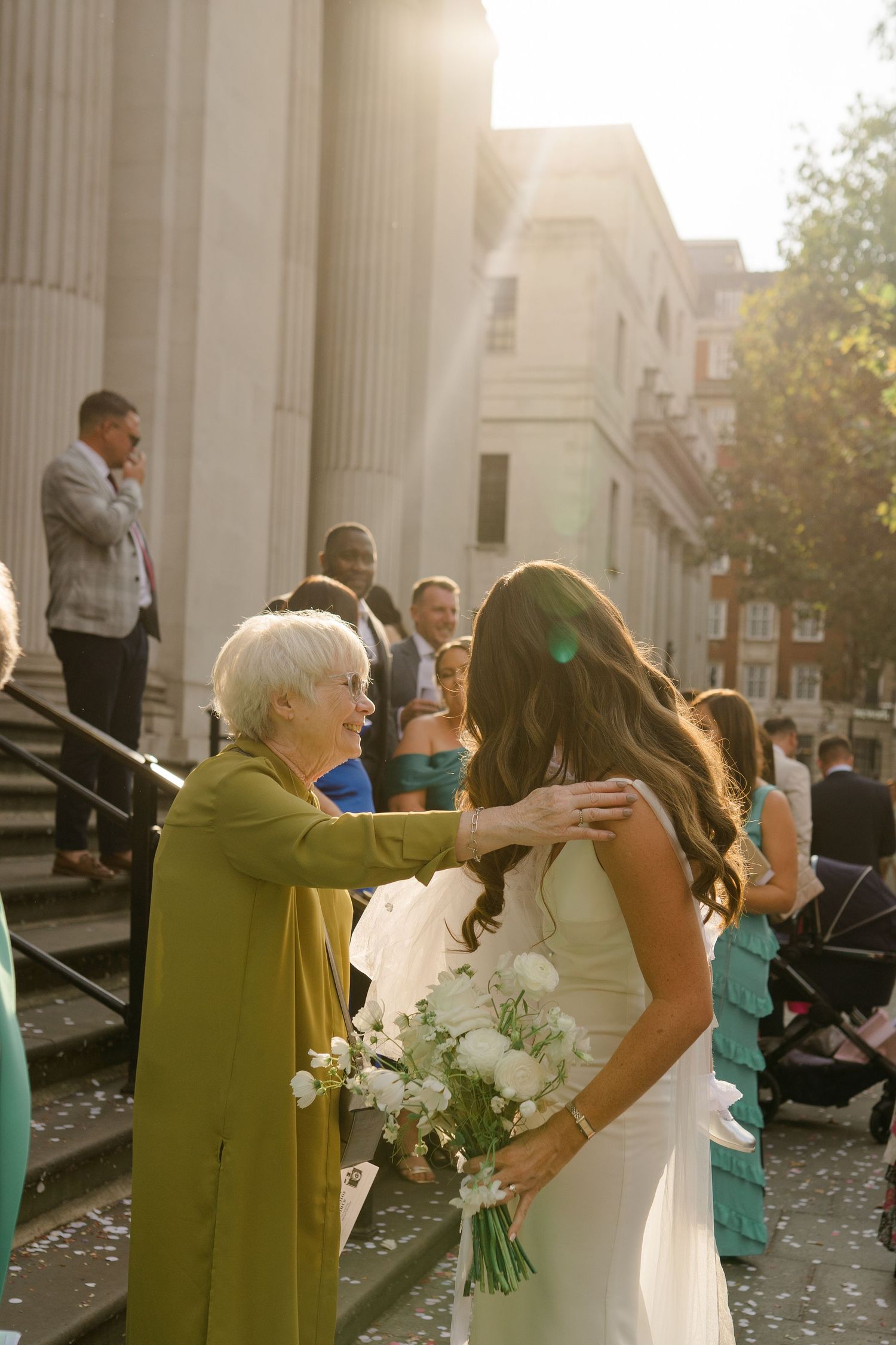 Wedding party poses on grand stone steps with white columns and turquoise bridesmaid dresses.