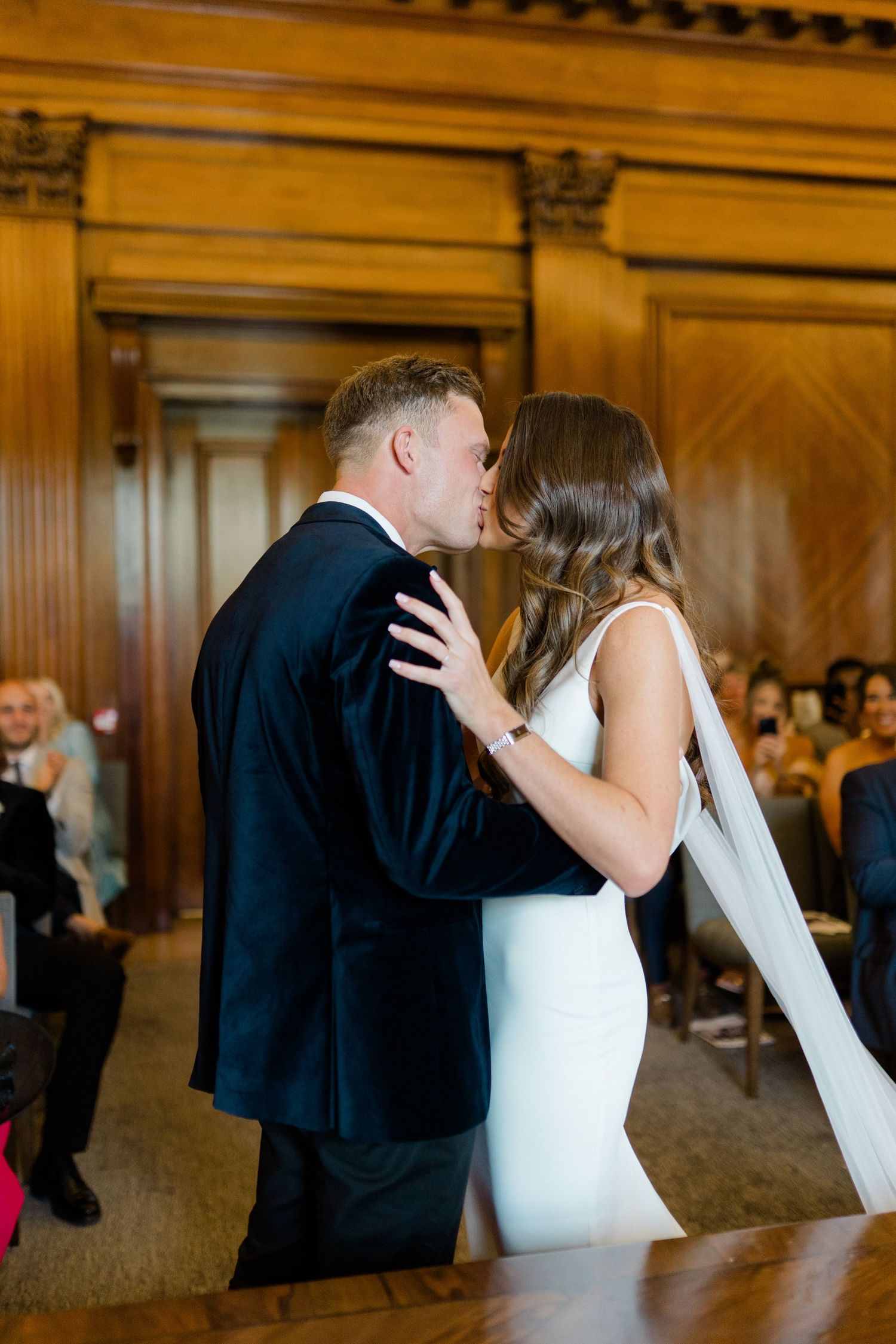 Romantic sequence of newlyweds sharing intimate kisses in a wood-paneled venue.