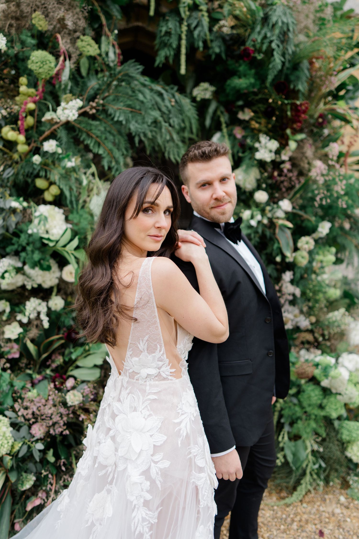 Romantic garden wedding portraits with white floral dress against green foliage backdrop.