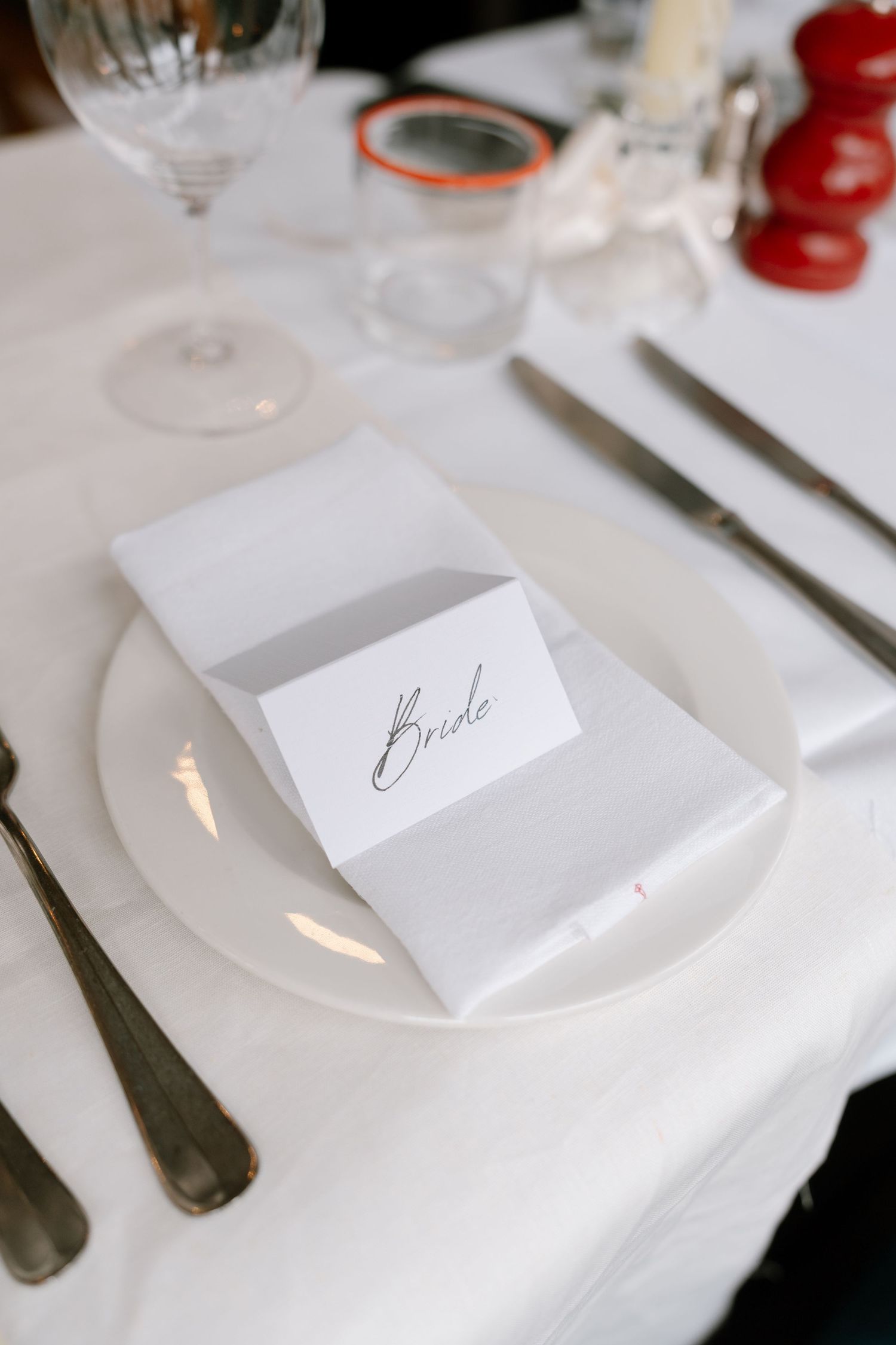 Elegant place settings with white plates and handwritten name cards on a formal dining table.