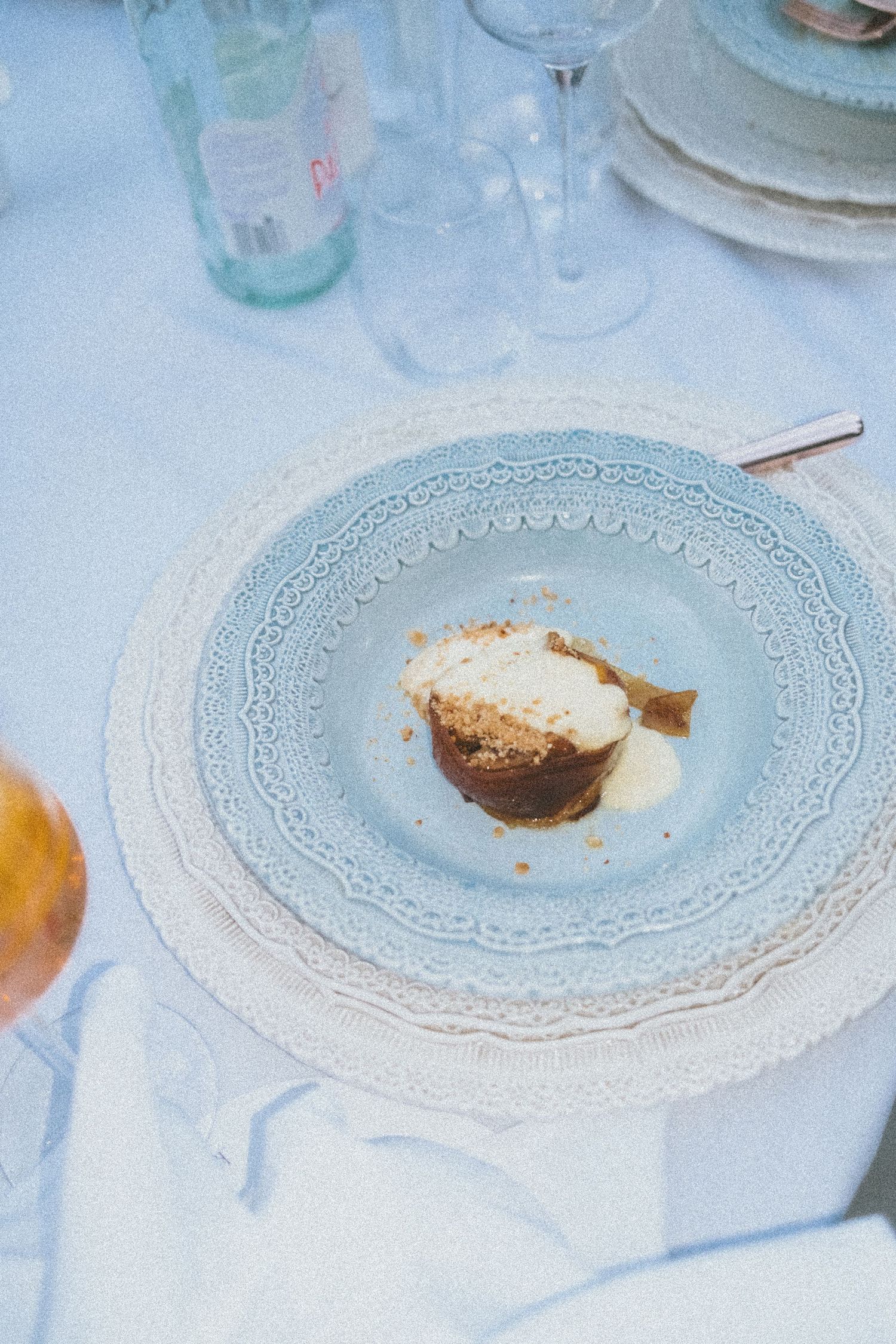 A plated dessert with cream and crumbs served on an ornate light blue and white patterned dish.