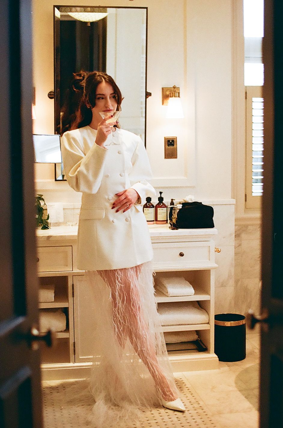 A person in a white top and flowing pink skirt dances gracefully in an elegant bathroom interior.
