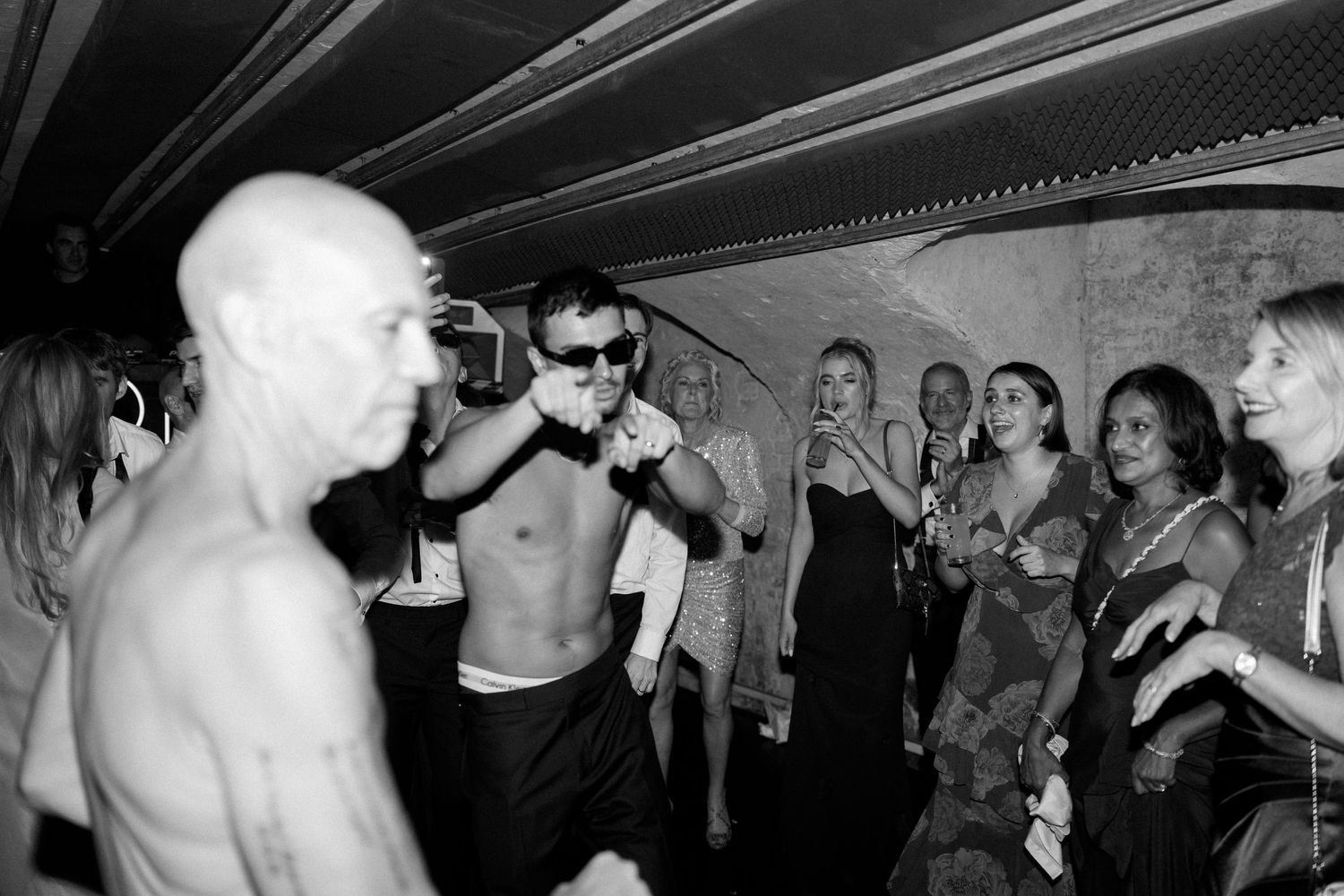 Black and white photo of guests watching a lively performance at a wedding after-party.