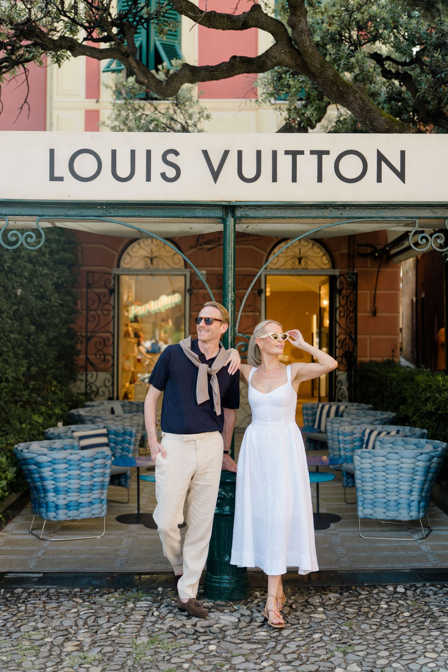 Stylish couple standing in front of Louis Vuitton store in Portofino, Italy on sunny day.