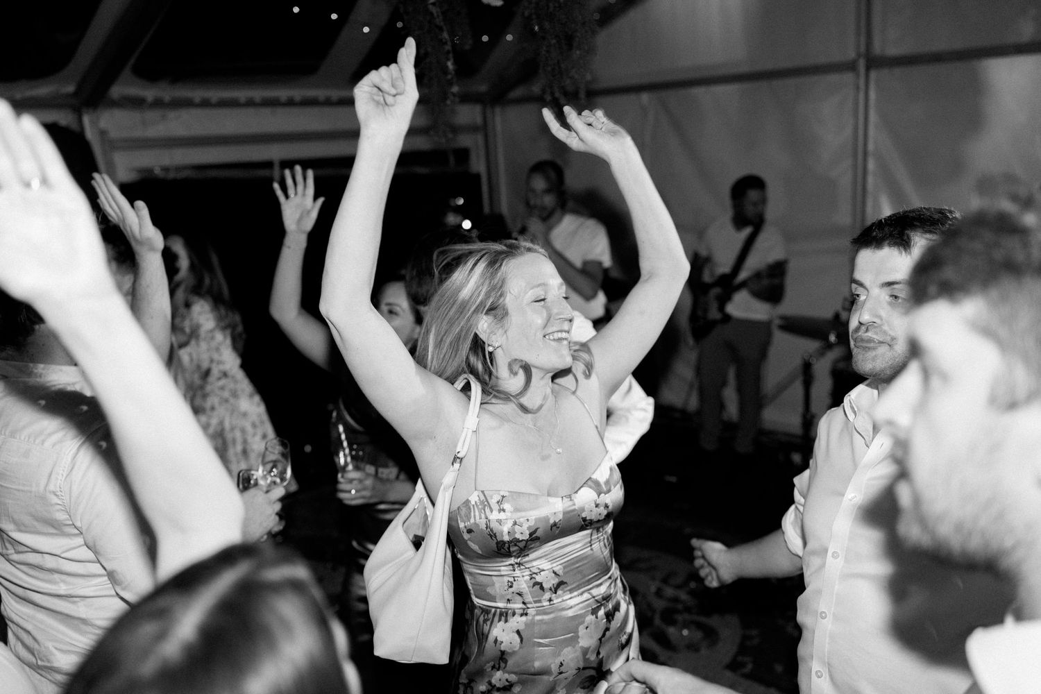 Wedding guests dancing and celebrating on a dimly lit dance floor.