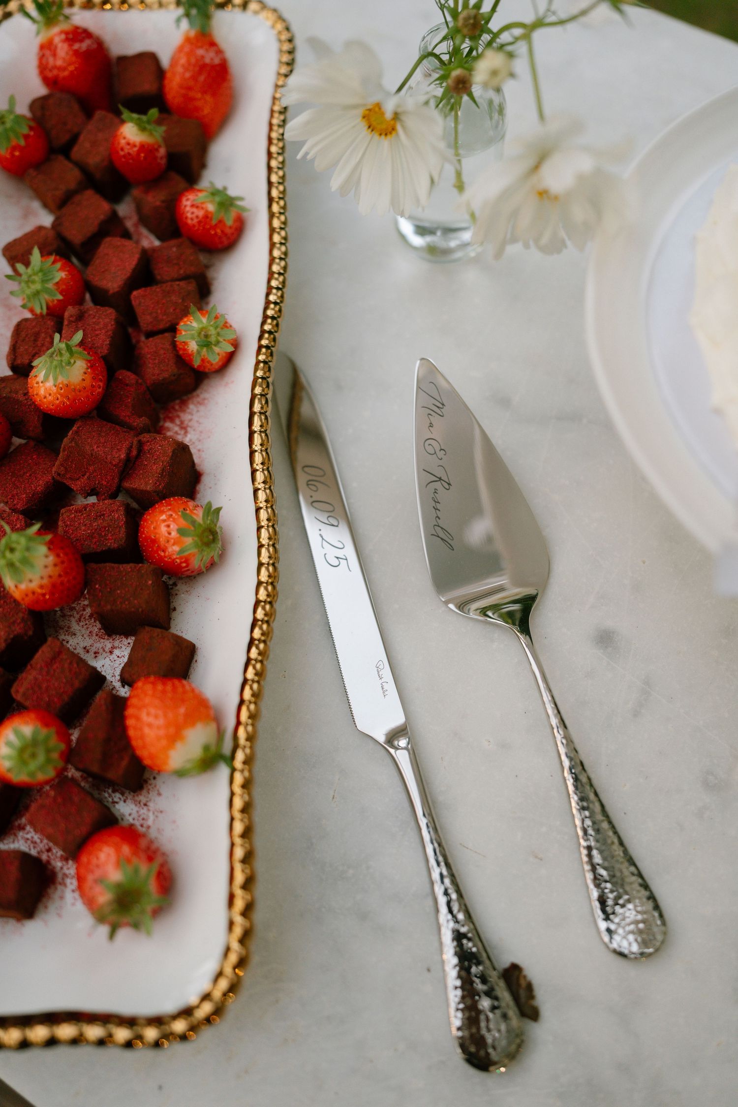 Elegant platter of chocolate-covered strawberries with gold trim and white floral accents.