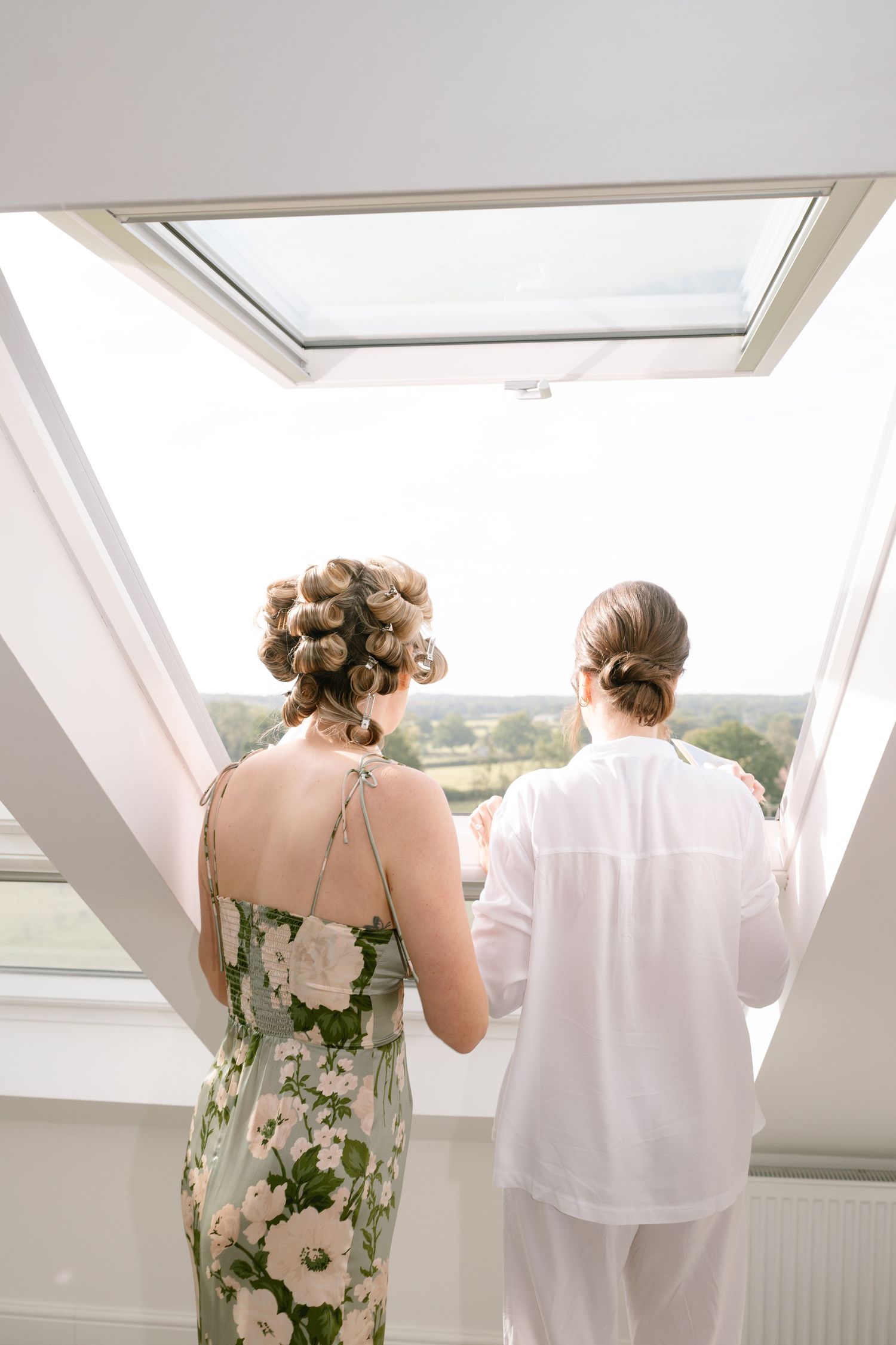 People in floral dress and white shirt looking out large skylight windows.