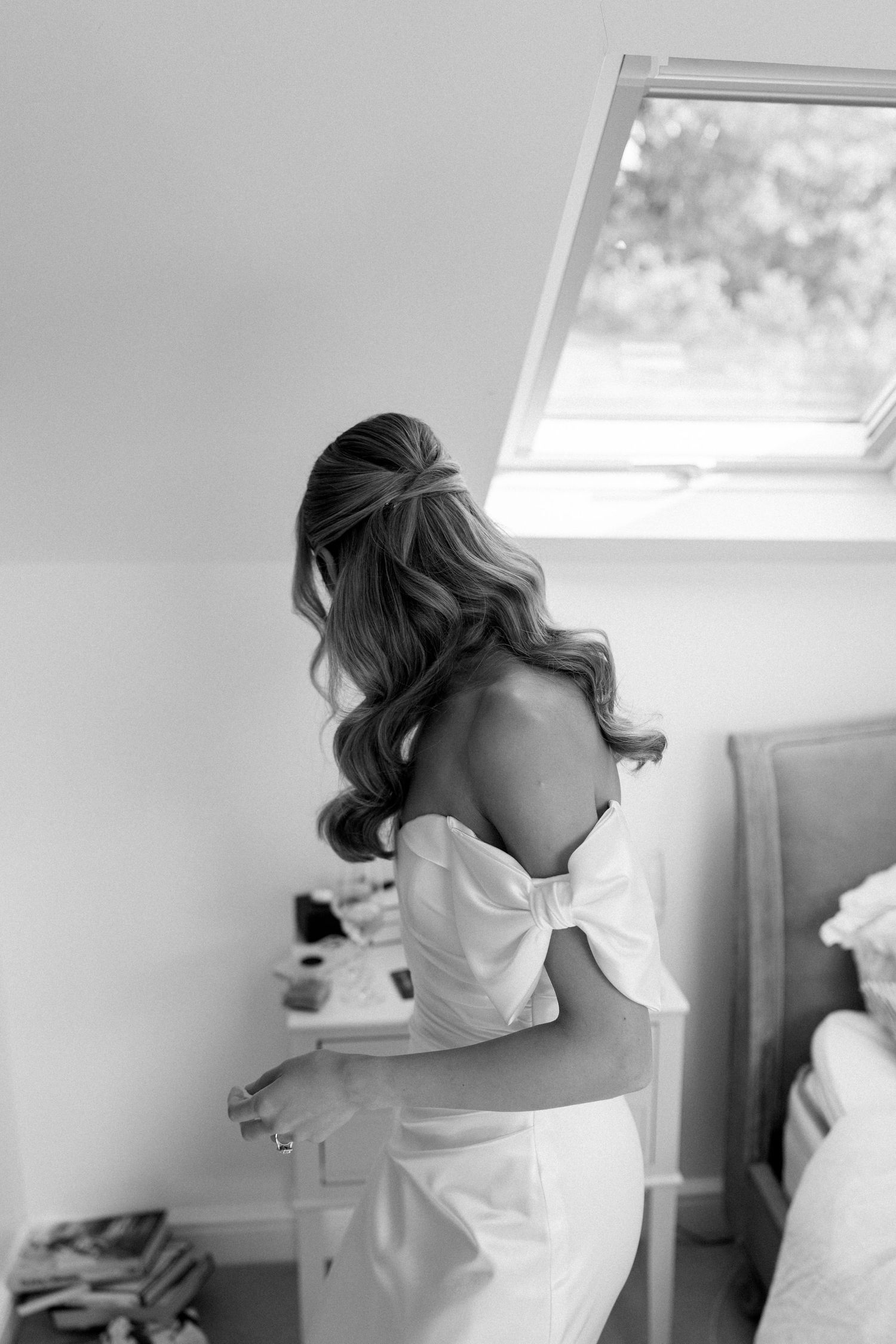 Artistic black and white photos of bridal preparation in sunlit room with skylights.