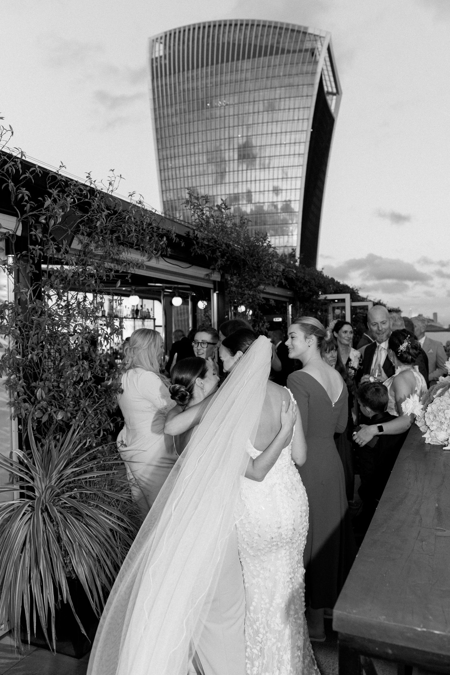 Elegant wedding celebration on a rooftop venue with guests mingling at dusk.