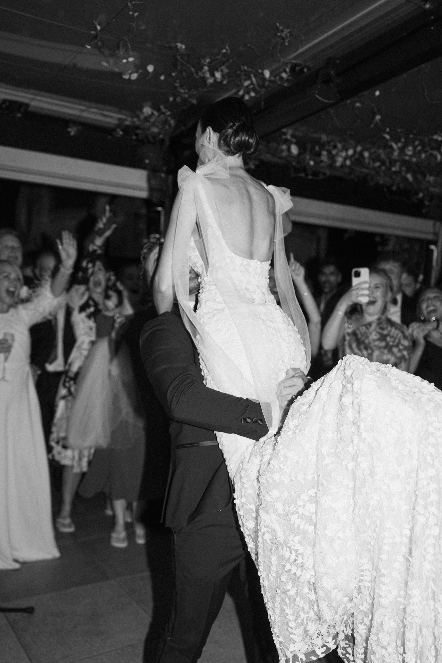 A couple shares an intimate dance moment at their wedding reception surrounded by guests.