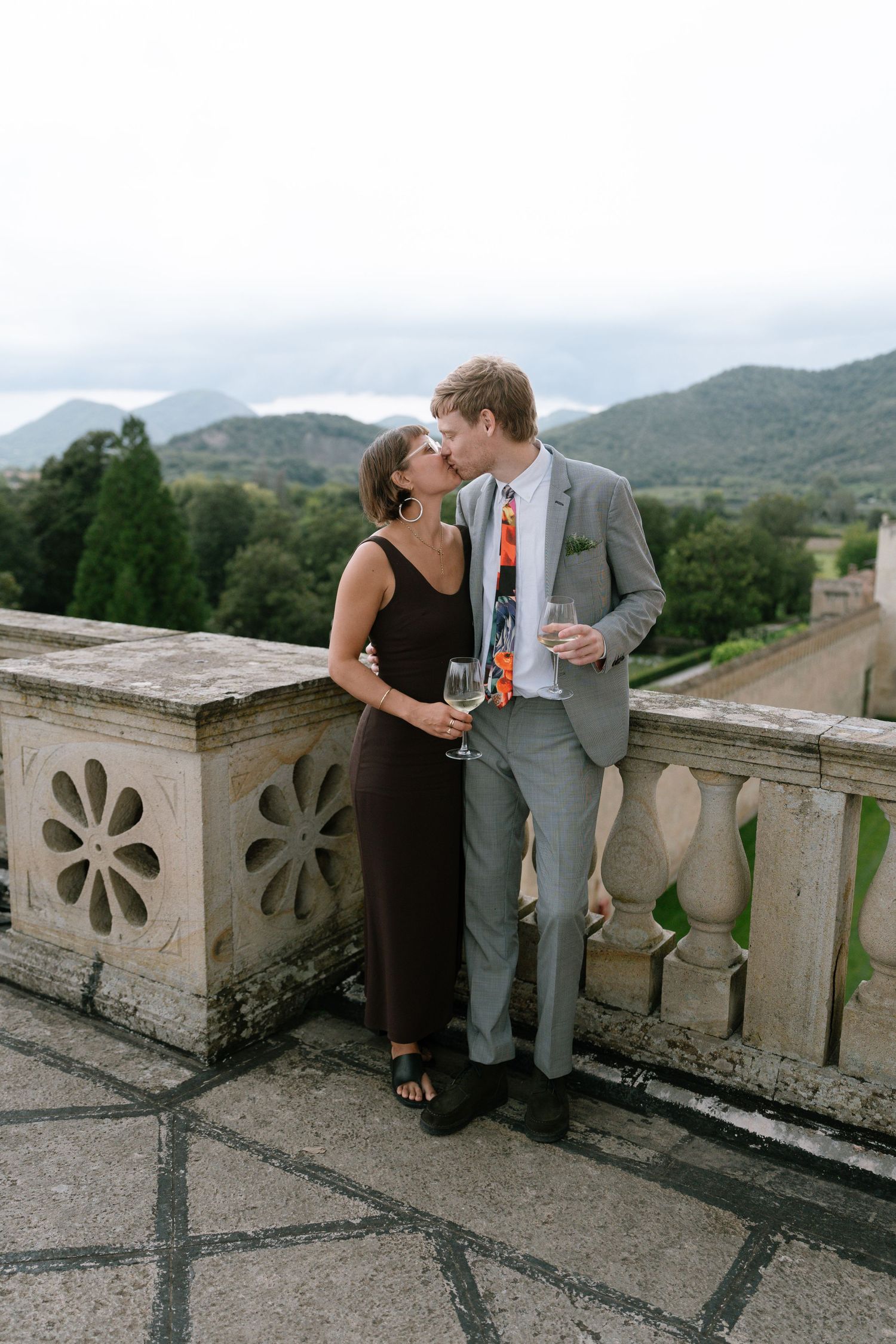 A couple sharing an intimate moment on a balcony overlooking mountain scenery.