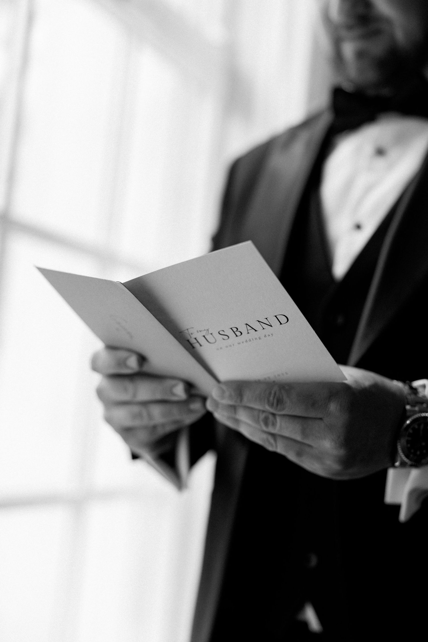 Close-up of hands holding a card that says 'Husband' in an elegant font.