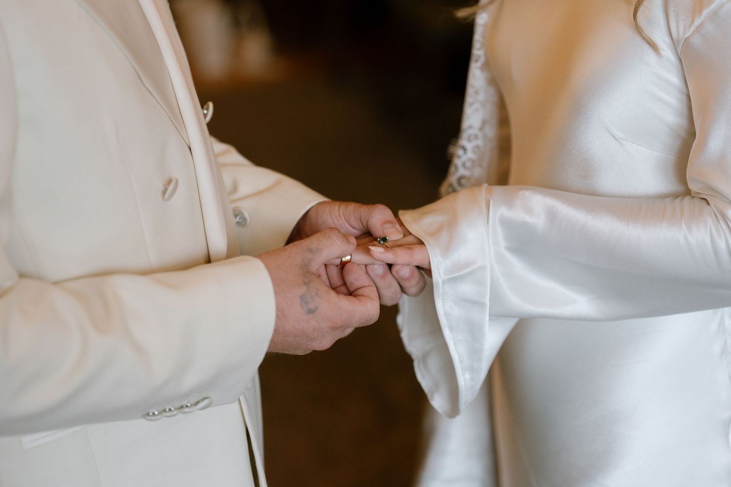 Close-up details of white wedding attire and accessories being adjusted.