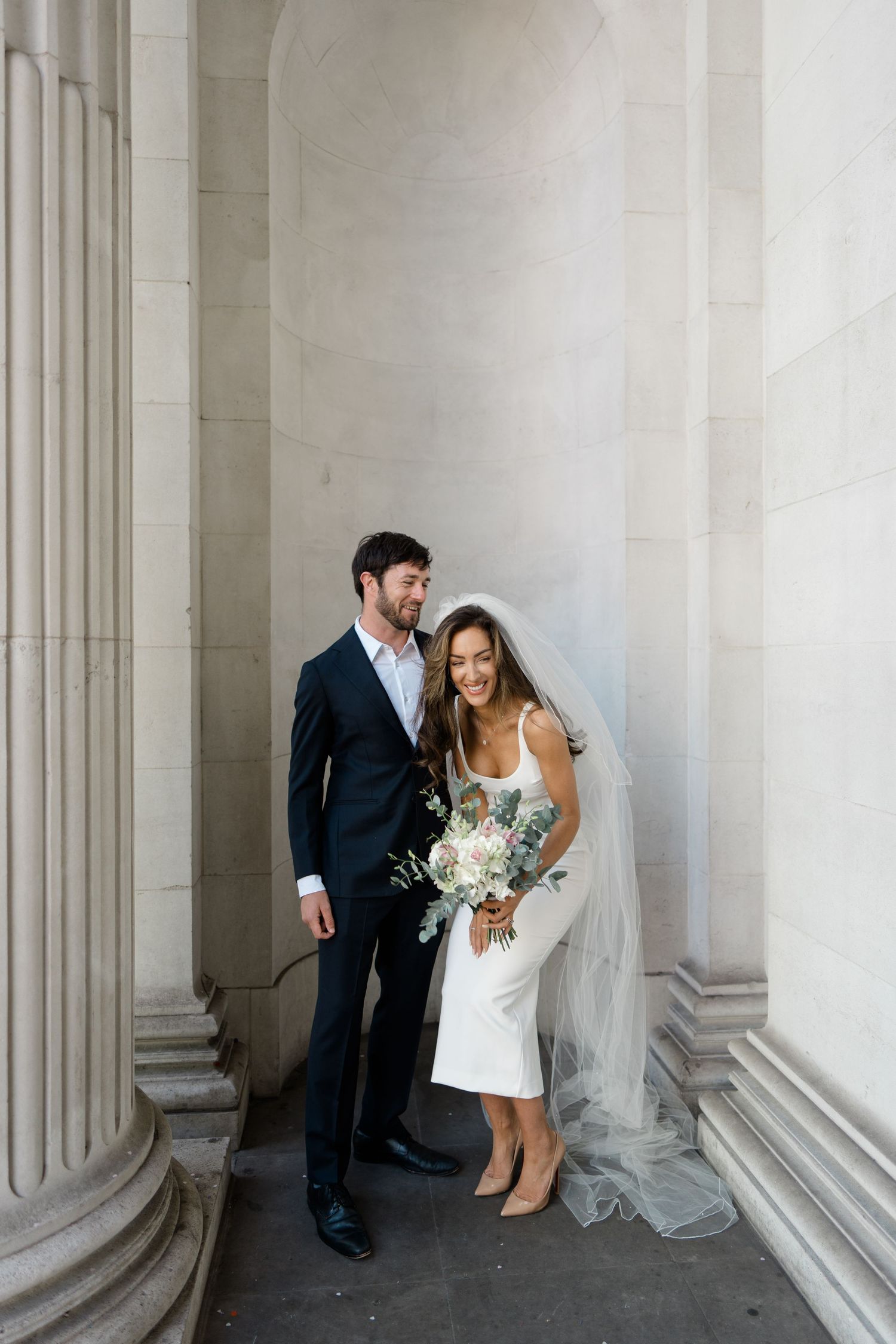 Architectural wedding portrait with classical columns creating elegant framing.