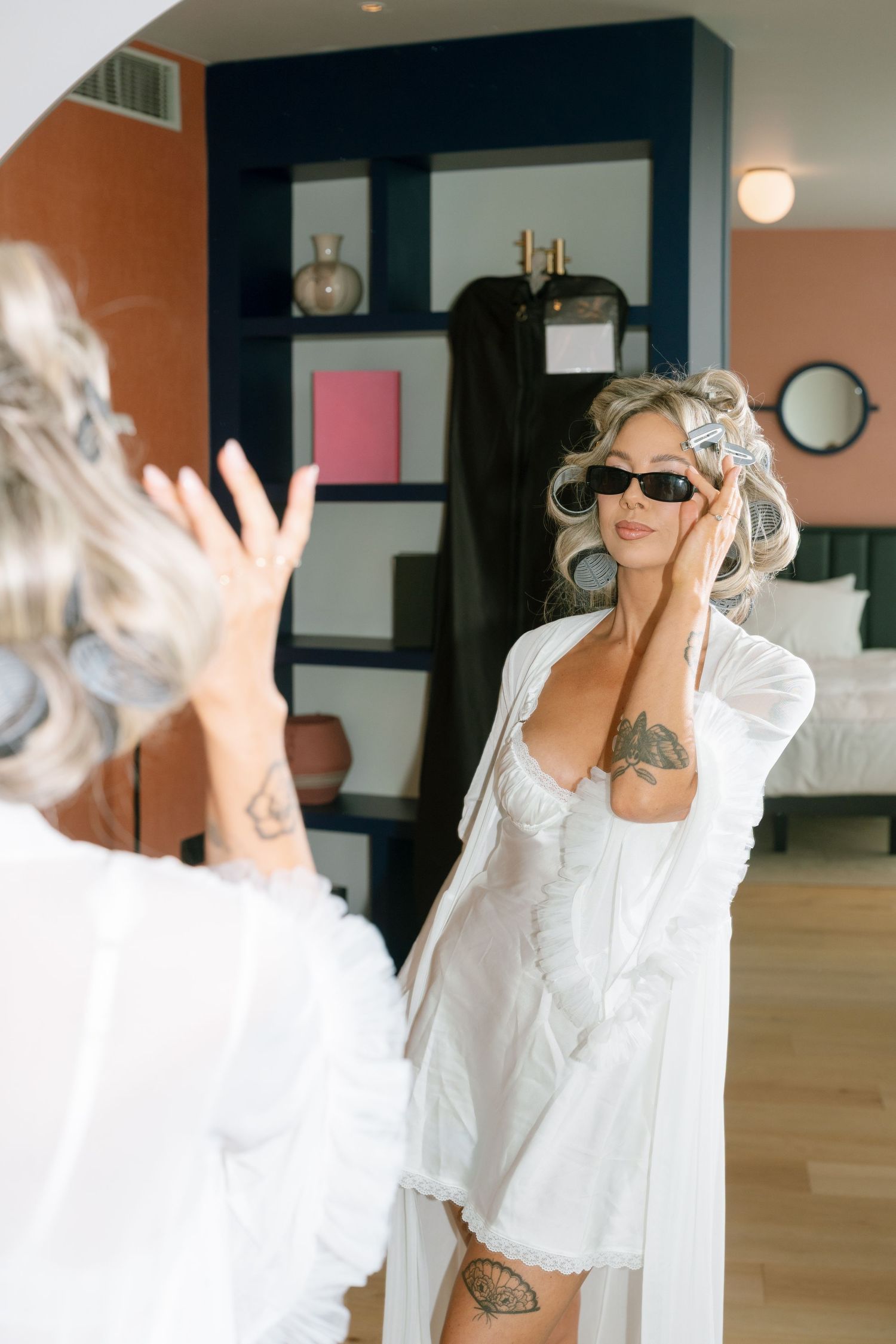 Woman in white lace robe dancing and celebrating in a modern room with coral walls.