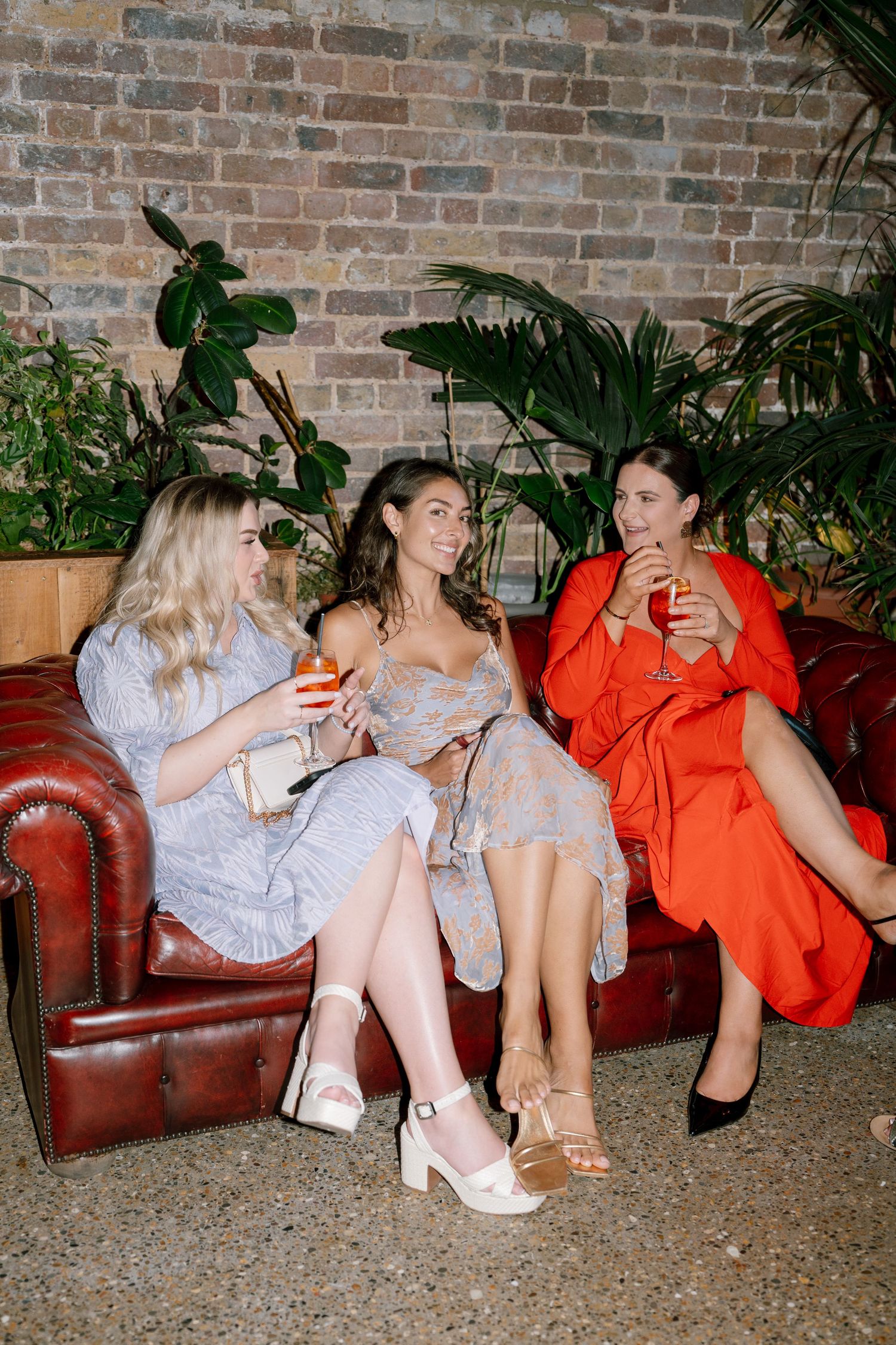 Friends relaxing on leather couches at a party while enjoying drinks together.