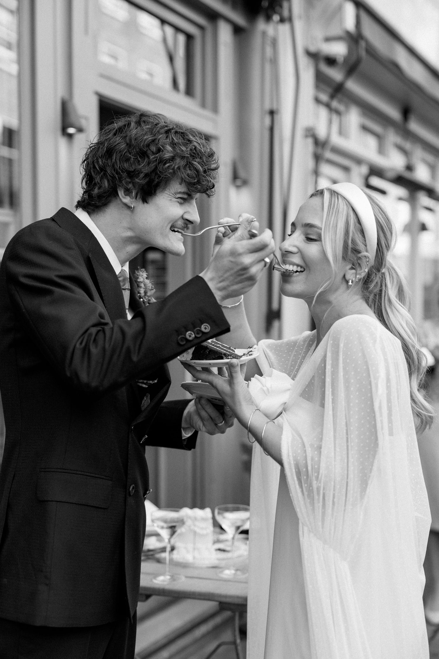 Black and white photos of a couple feeding each other cake at their wedding reception.