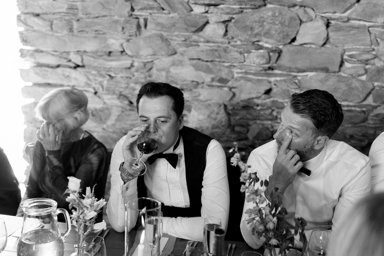 Wedding guests enjoying a formal dinner reception in a rustic stone venue with elegant decor.