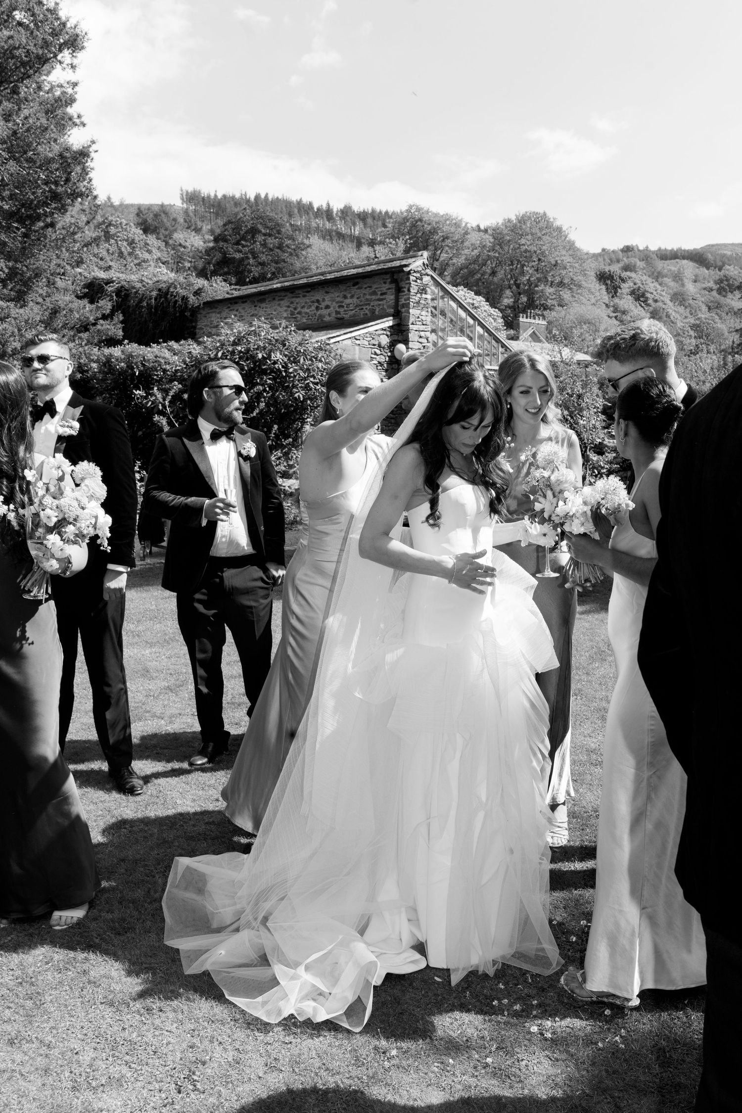 Black and white wedding photo showing celebration in front of rustic stone building.