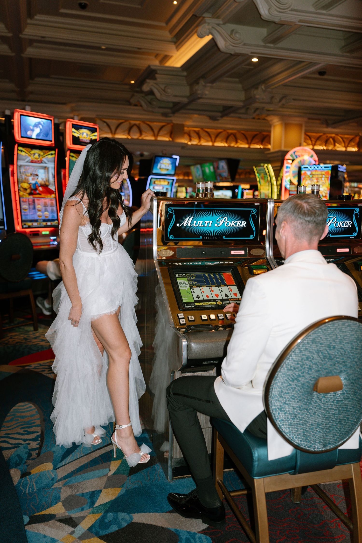 Newlyweds explore a Las Vegas casino floor surrounded by slot machines.