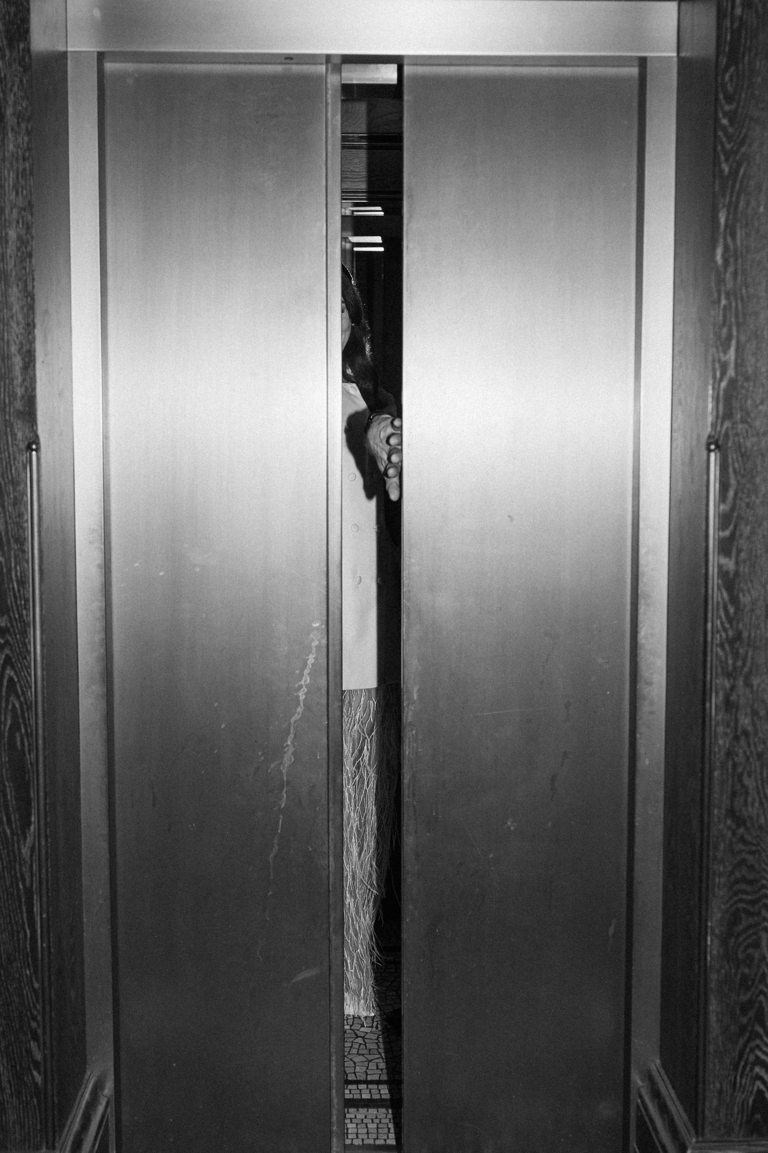 Black and white photo of elevator doors slightly open at wedding venue.