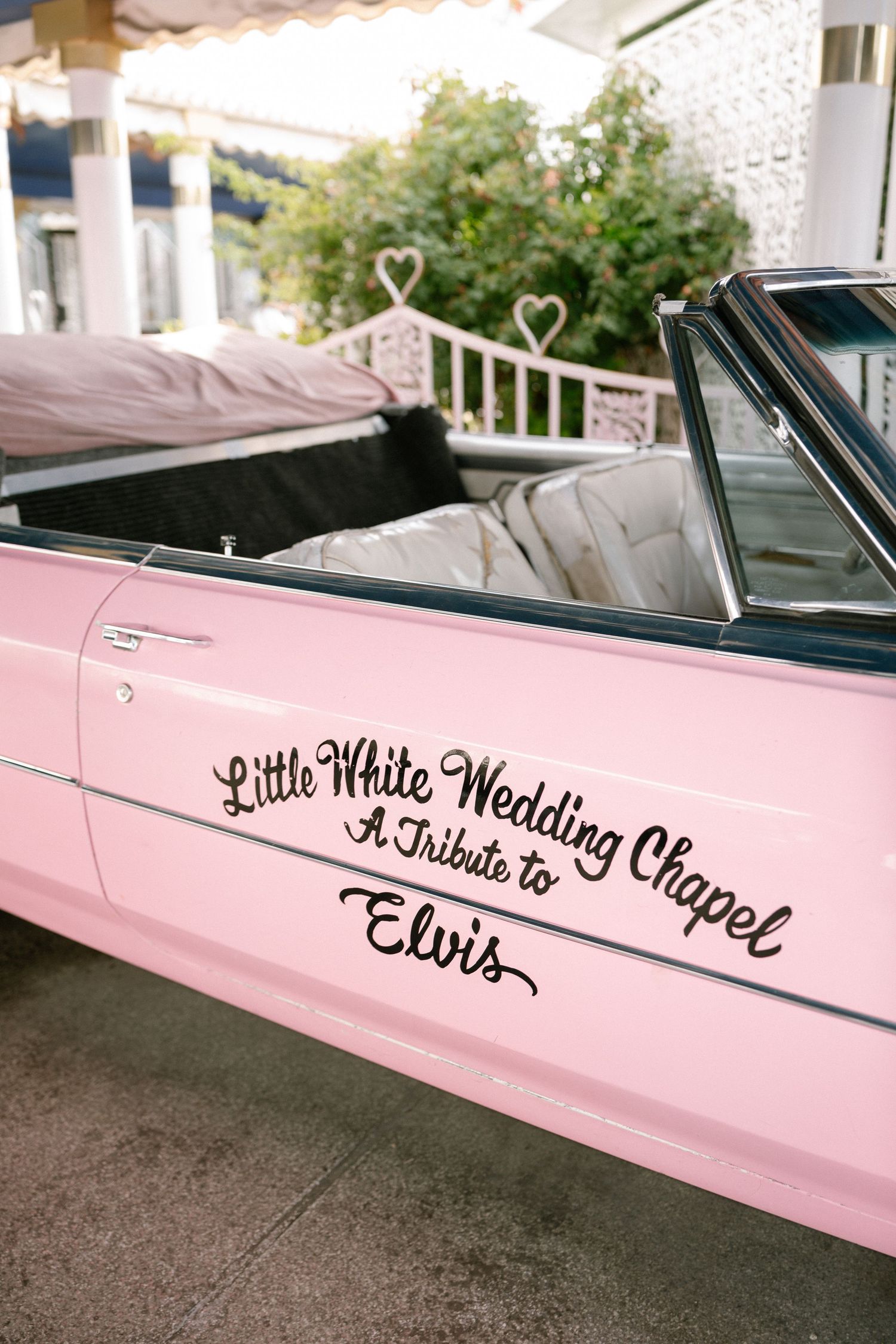 Pink classic car with 'Little White Wedding Chapel' text on the side.