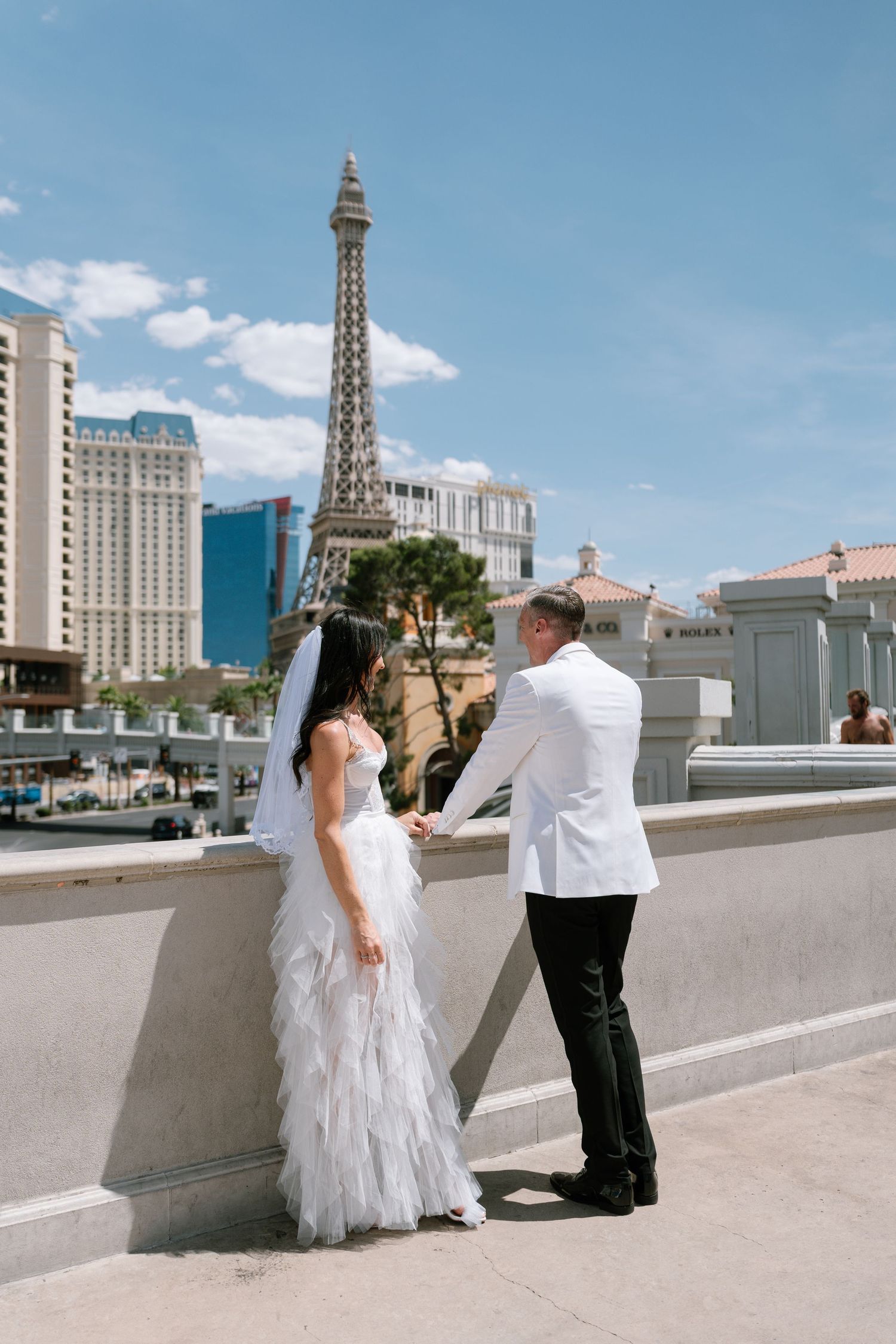 Wedding couple taking photos on a rooftop with the Las Vegas Strip and Paris Hotel in the background.