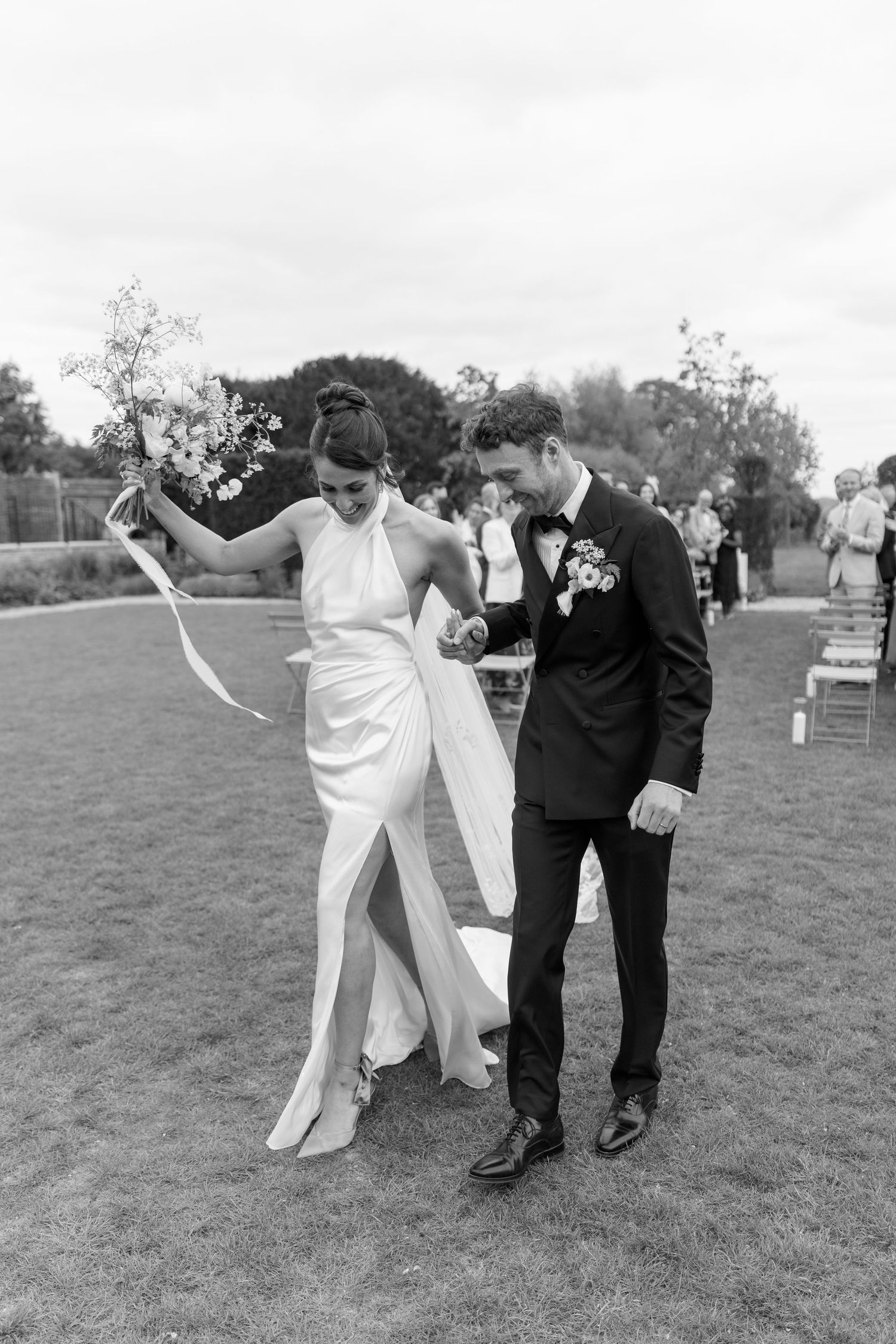 Bride and groom walking down the aisle on a lawn after their outdoor wedding ceremony.