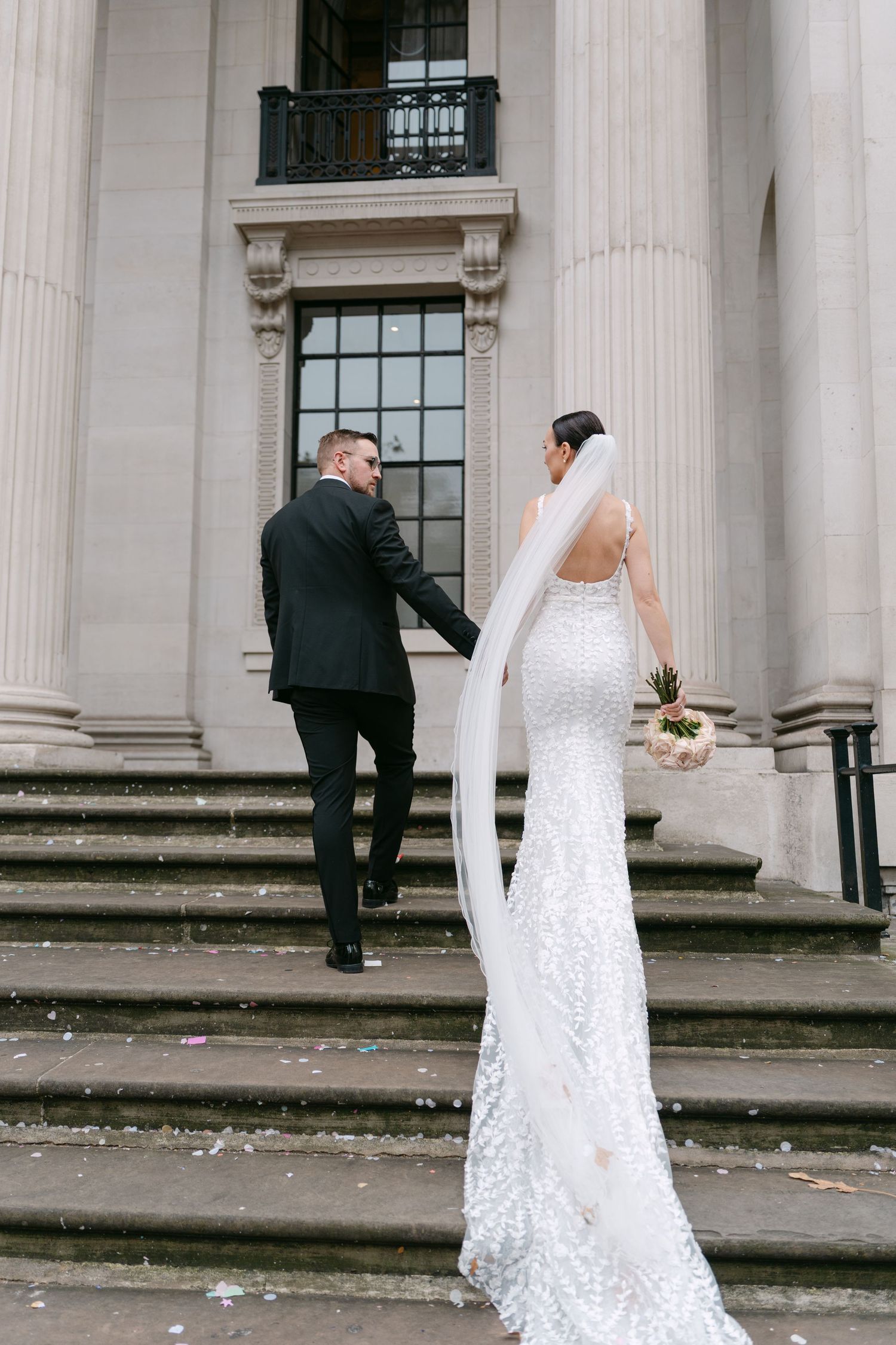 Candid wedding photos showing couple walking near classical stone columns.