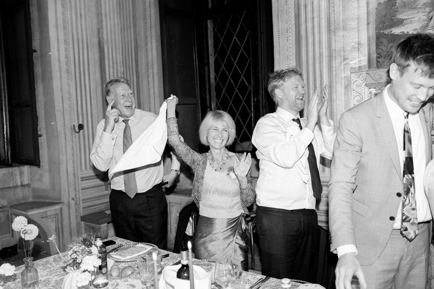 Black and white photograph capturing celebratory moments at a formal ballroom event.