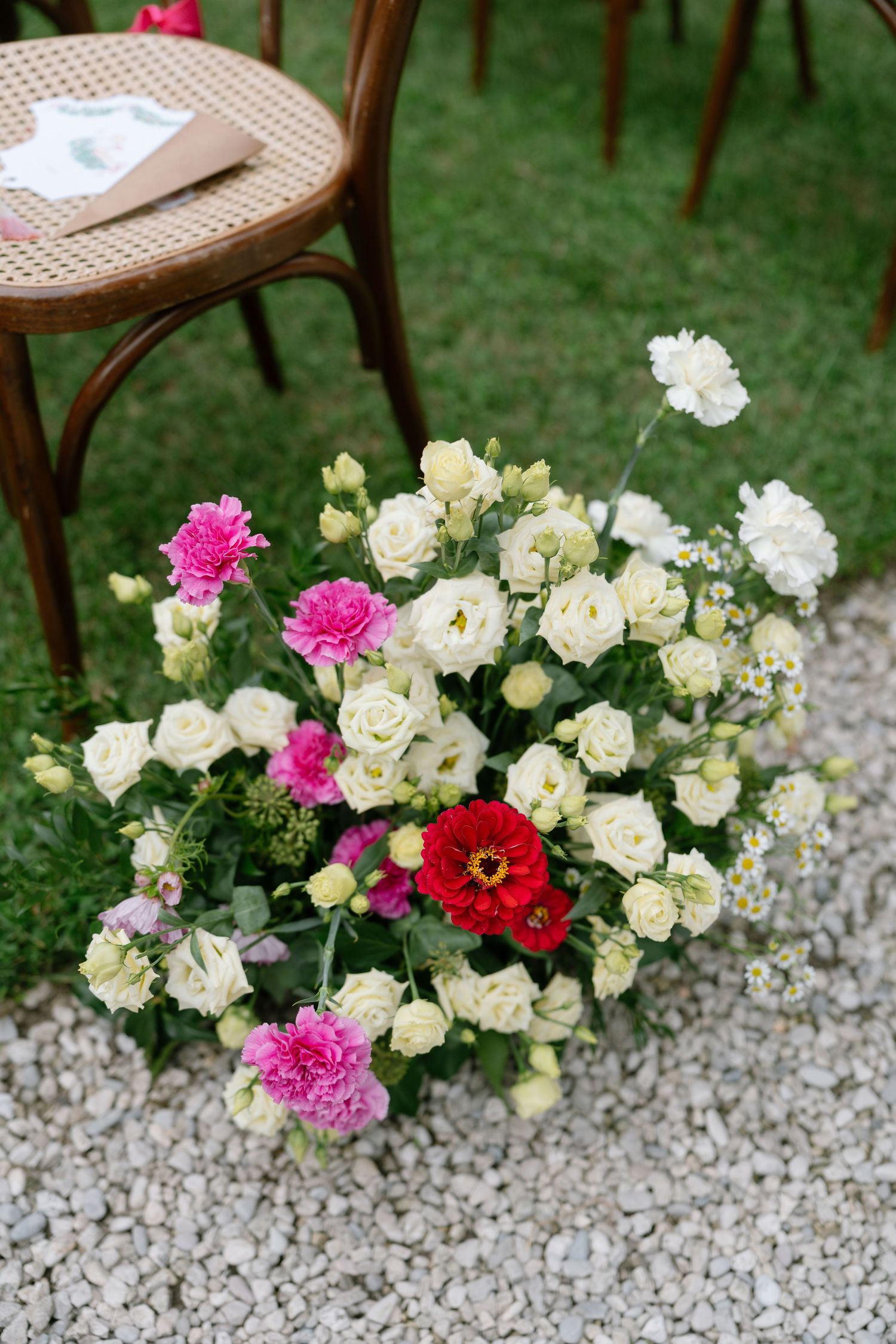 Colorful garden roses and flowers decorate the edge of a gravel pathway.