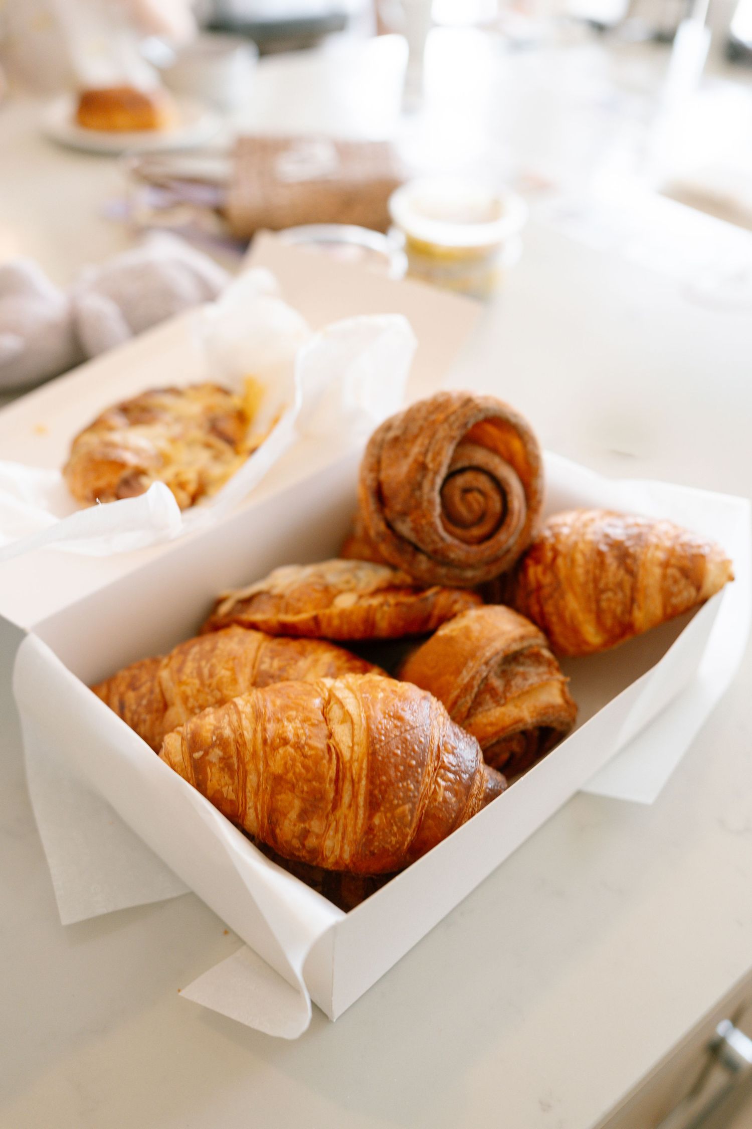 Fresh golden croissants displayed in white paper-lined boxes.
