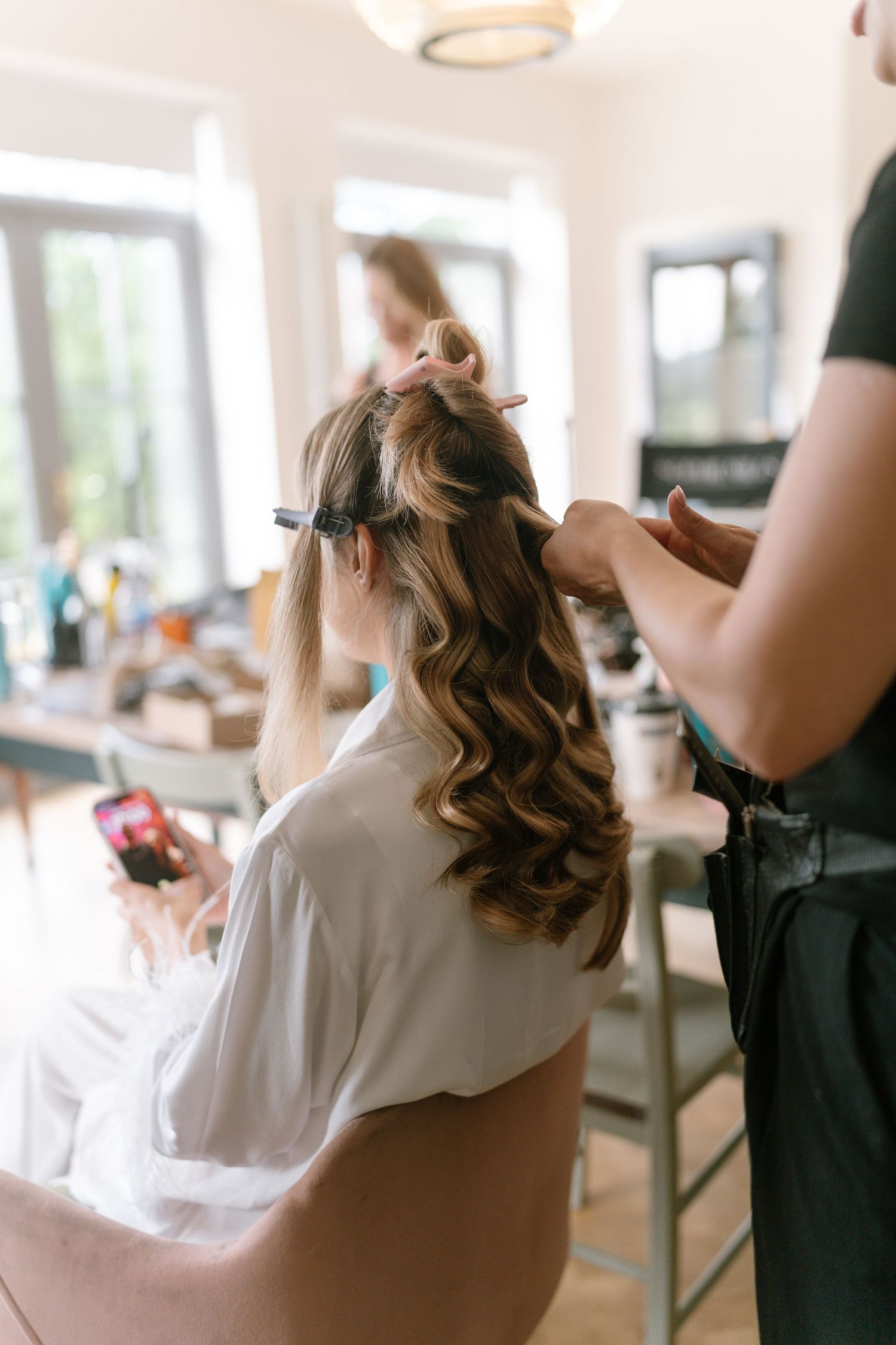 Professional hair styling session in progress with curling tools.