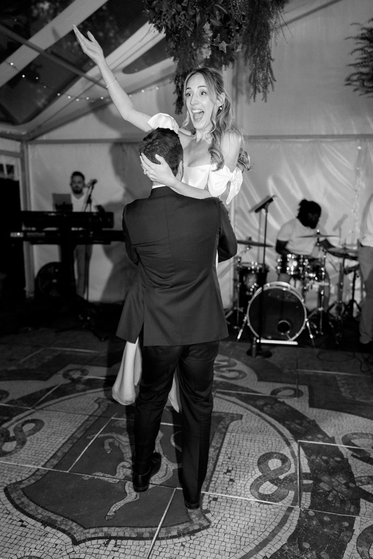 Black and white photo of dancers on an ornate patterned floor at a wedding reception.