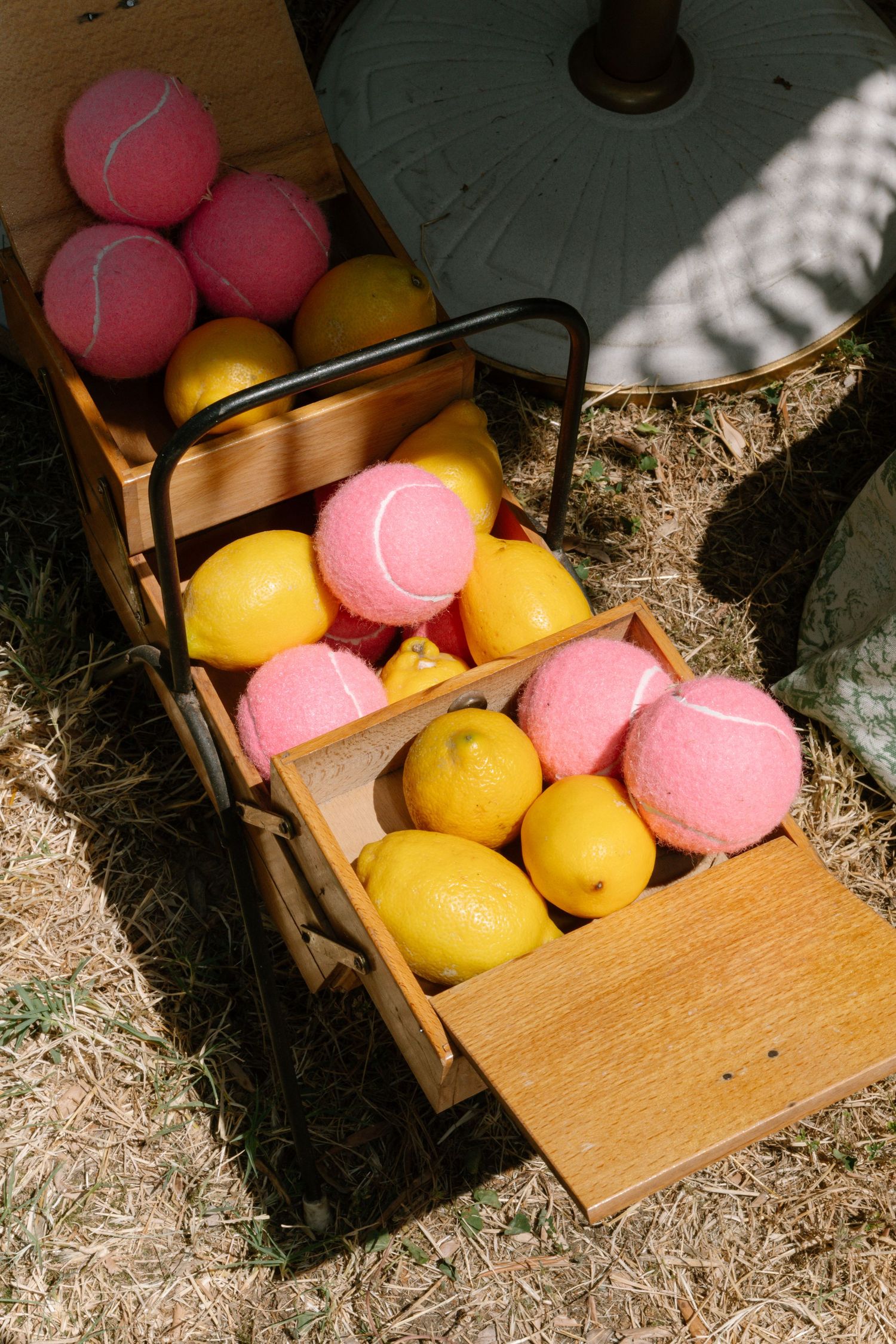 Wooden box filled with pink and yellow tennis balls sitting in straw.