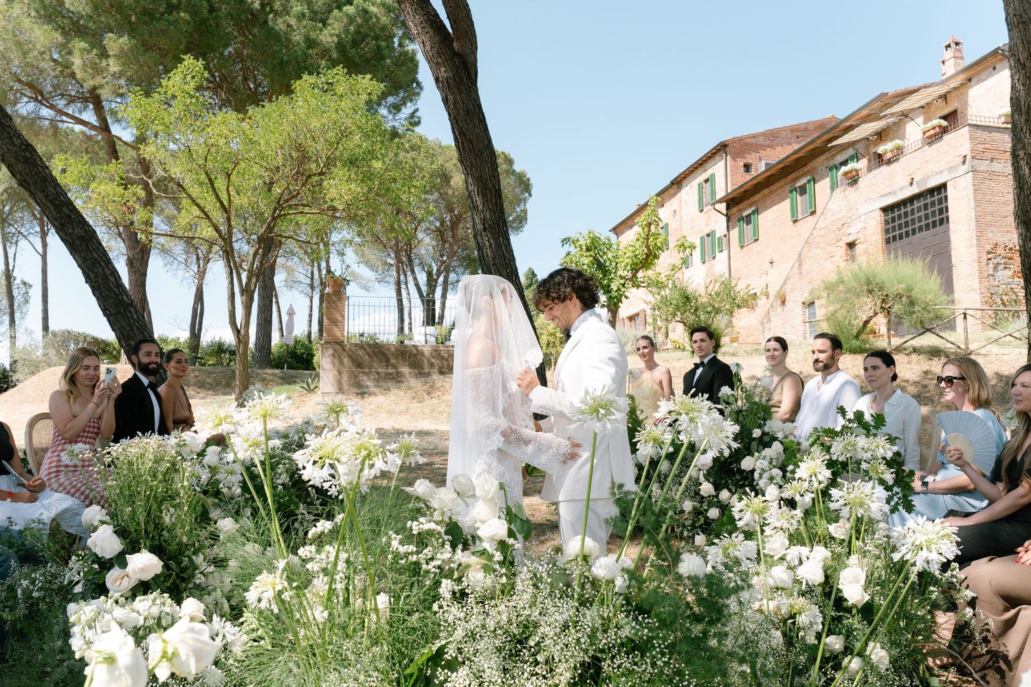 Outdoor wedding ceremony site decorated with white flowers and greenery in Tuscany.