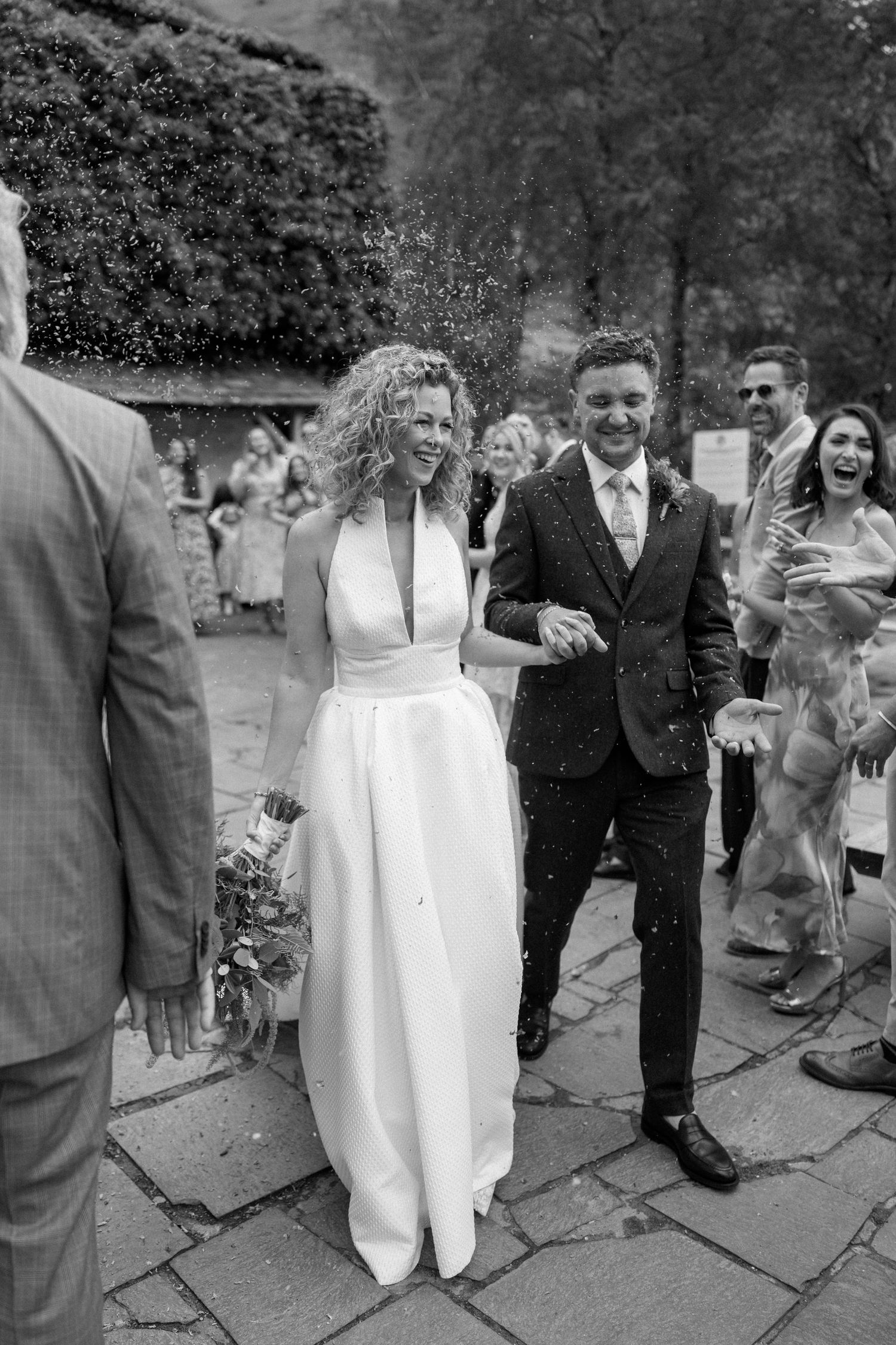 Wedding party and guests celebrating on stone patio during outdoor reception.