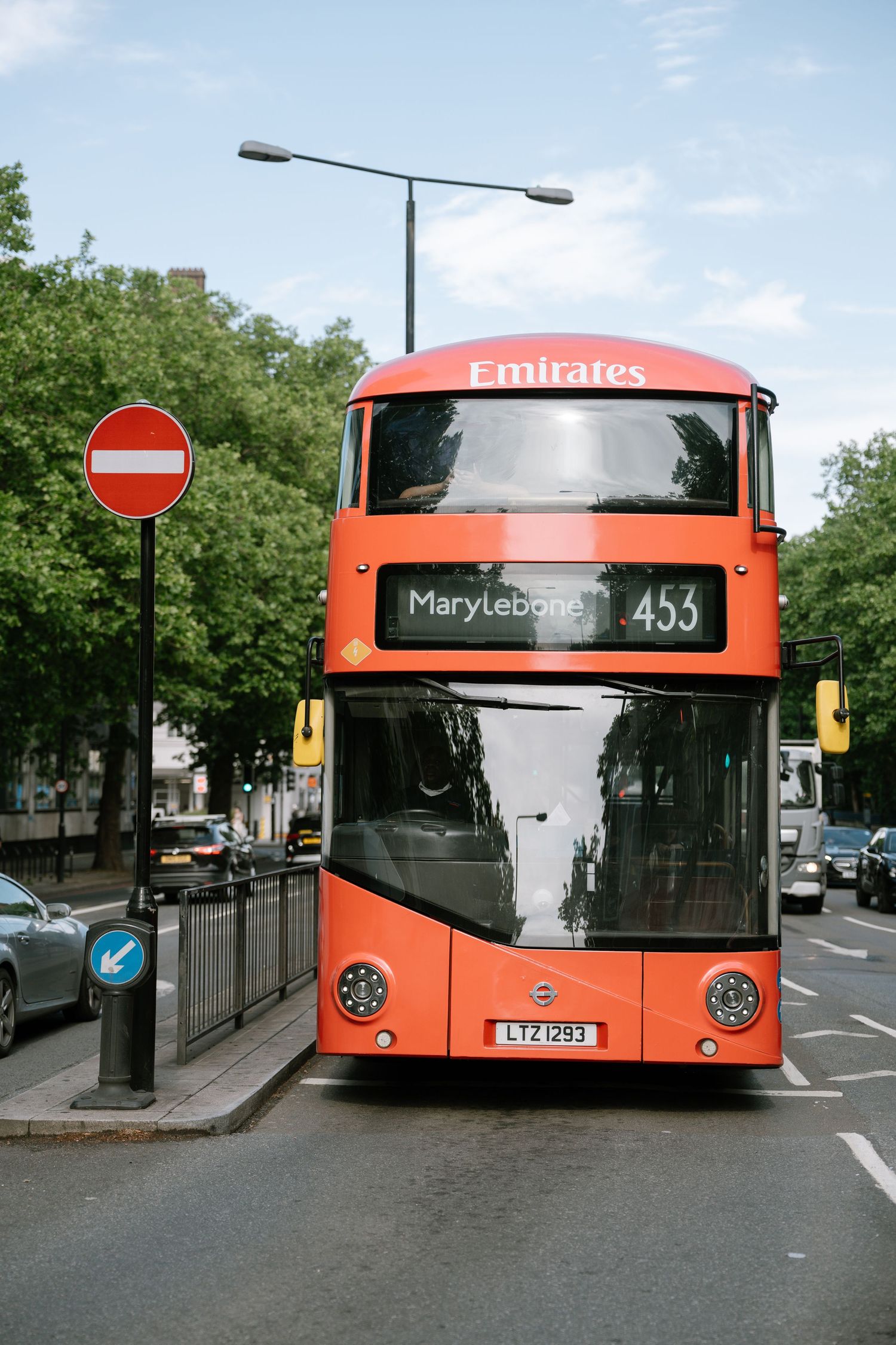 A red London double decker bus numbered 453 to Marylebone stands on a city street near a no entry sign.