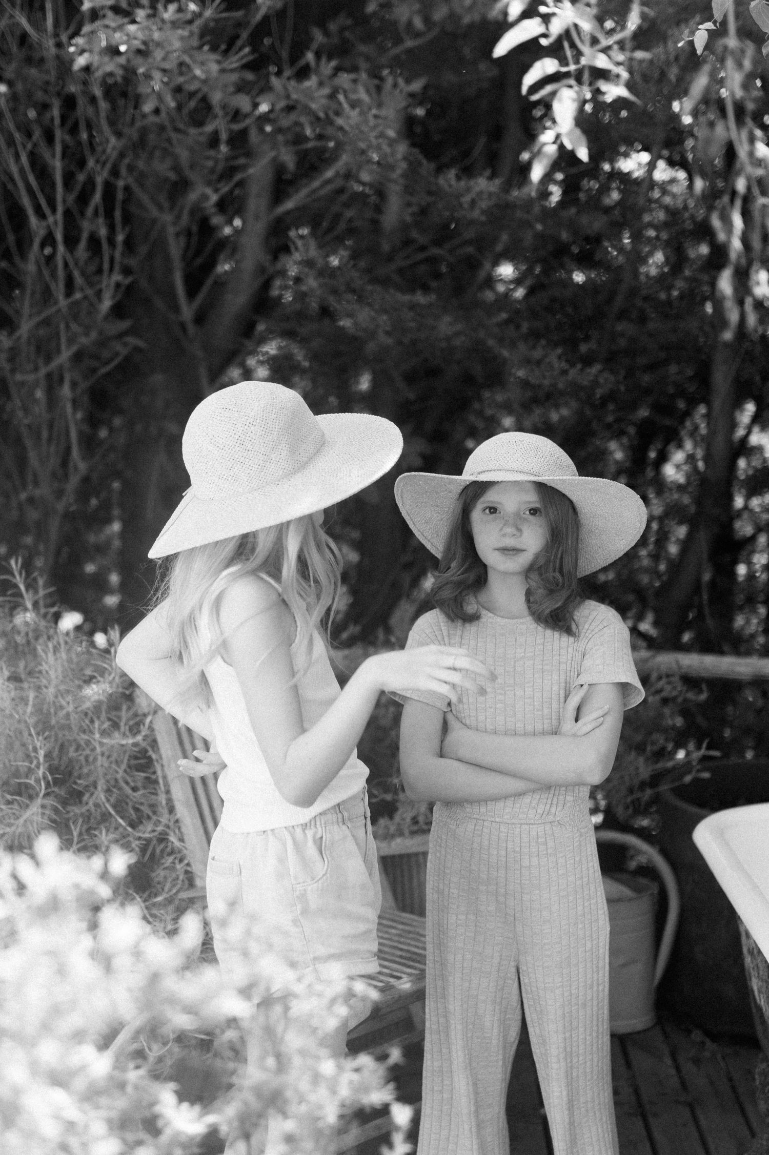 Children in white sun hats playing dress up on a wooden deck.
