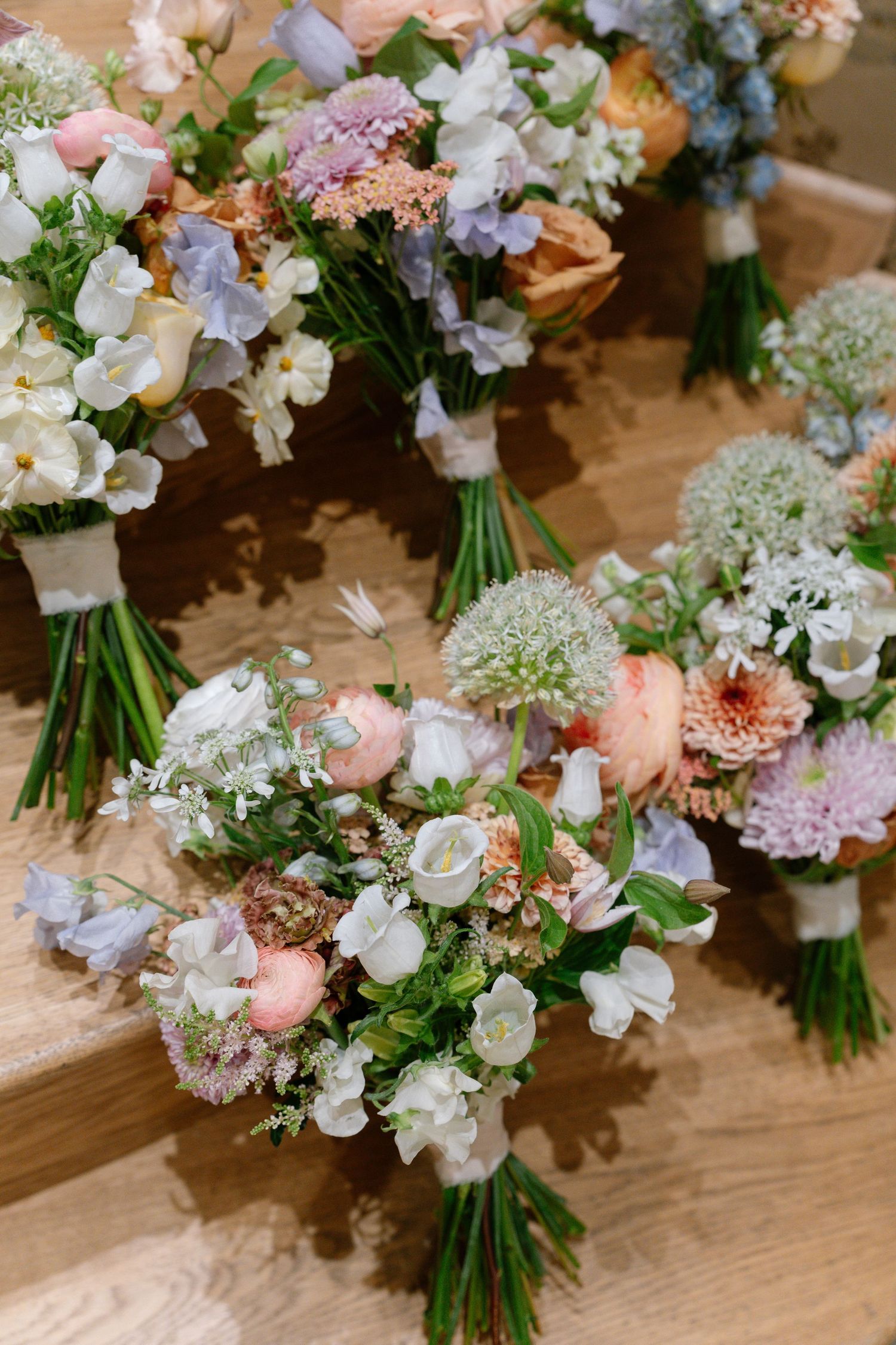 Multiple bridal bouquets featuring soft pink and white flowers tied with ribbons.