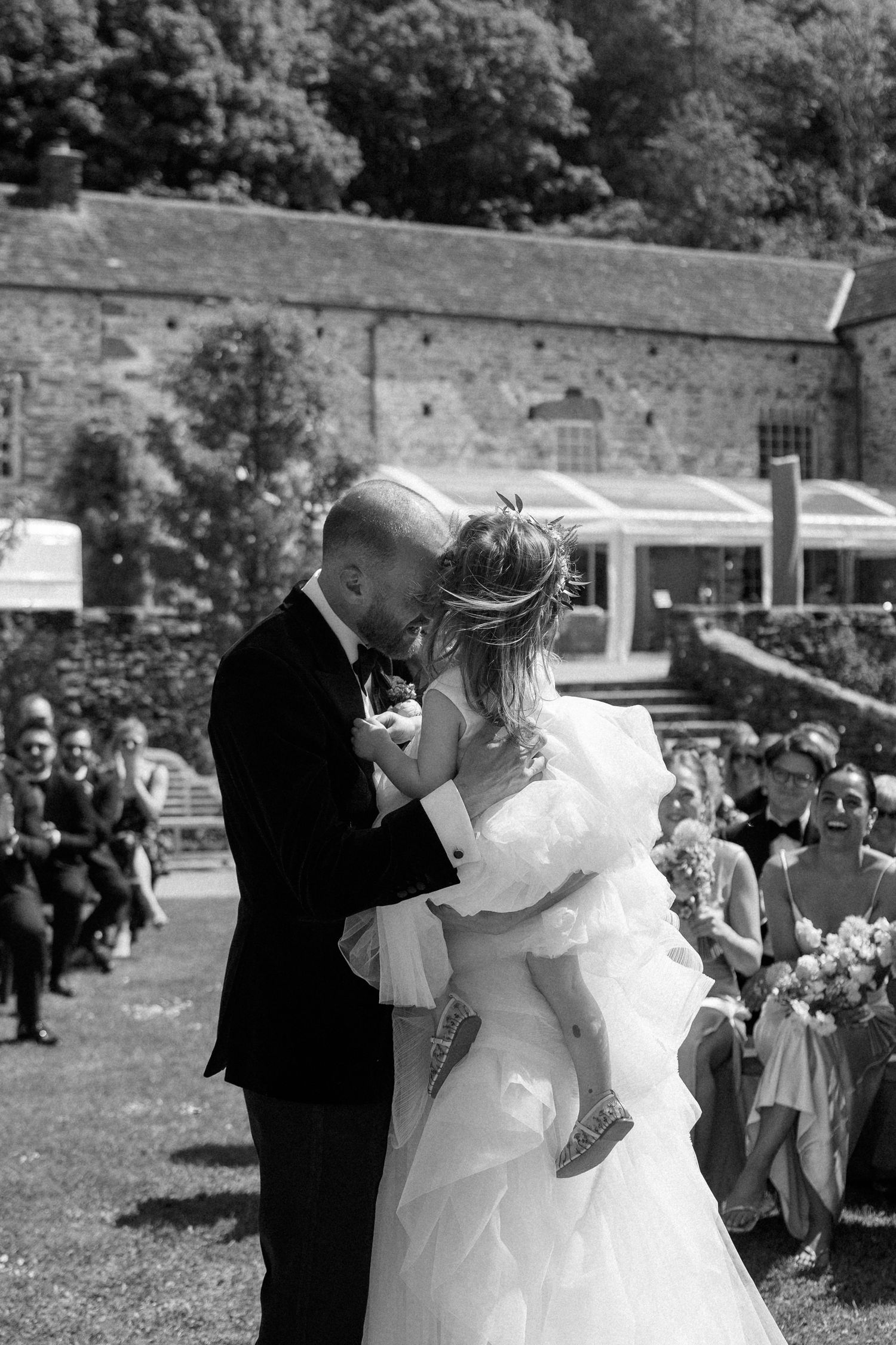 Black and white wedding photo sequence captures a couple's first kiss during their outdoor ceremony.