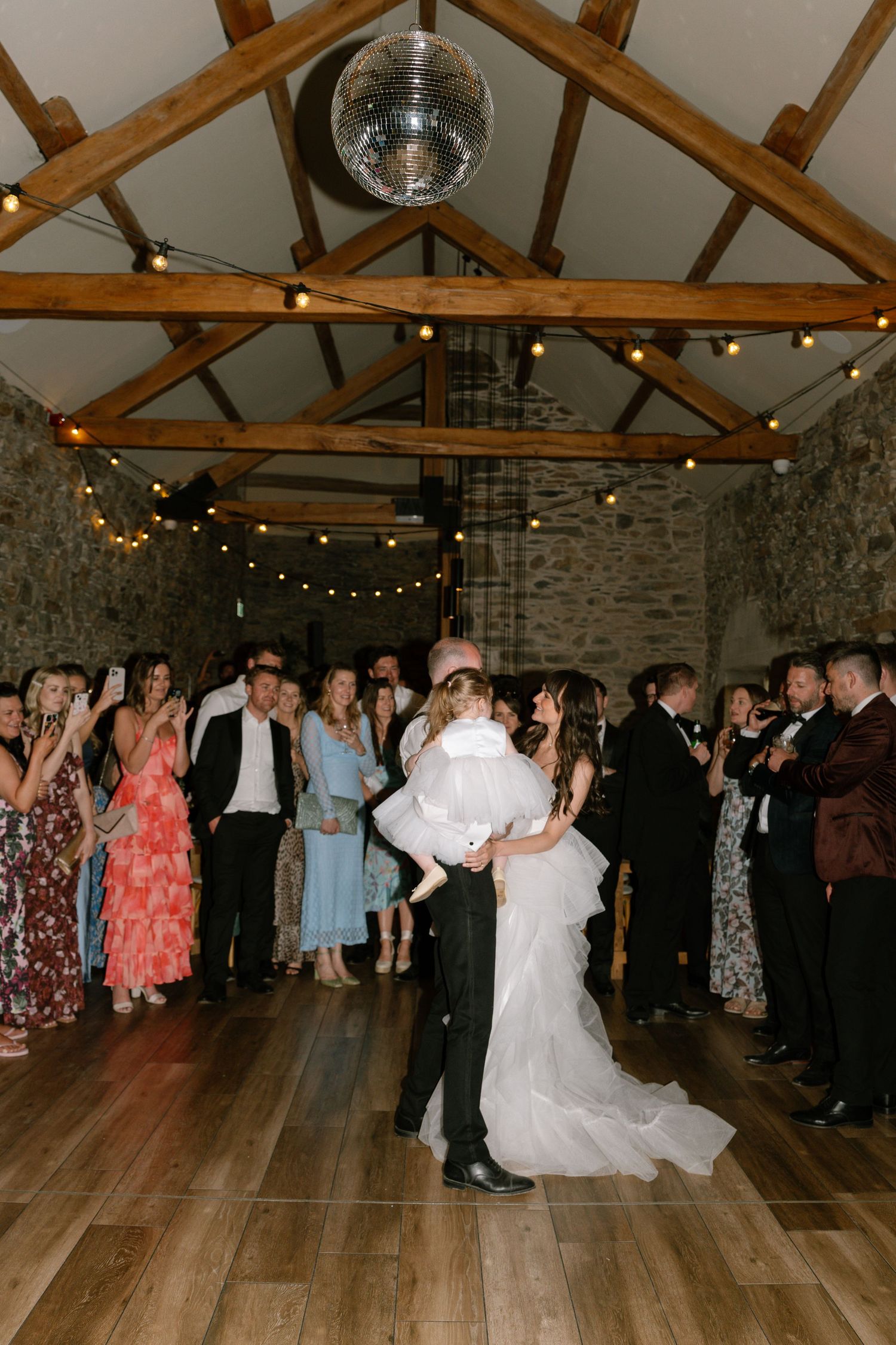 Wedding reception in a rustic barn venue with exposed beams and string lights.