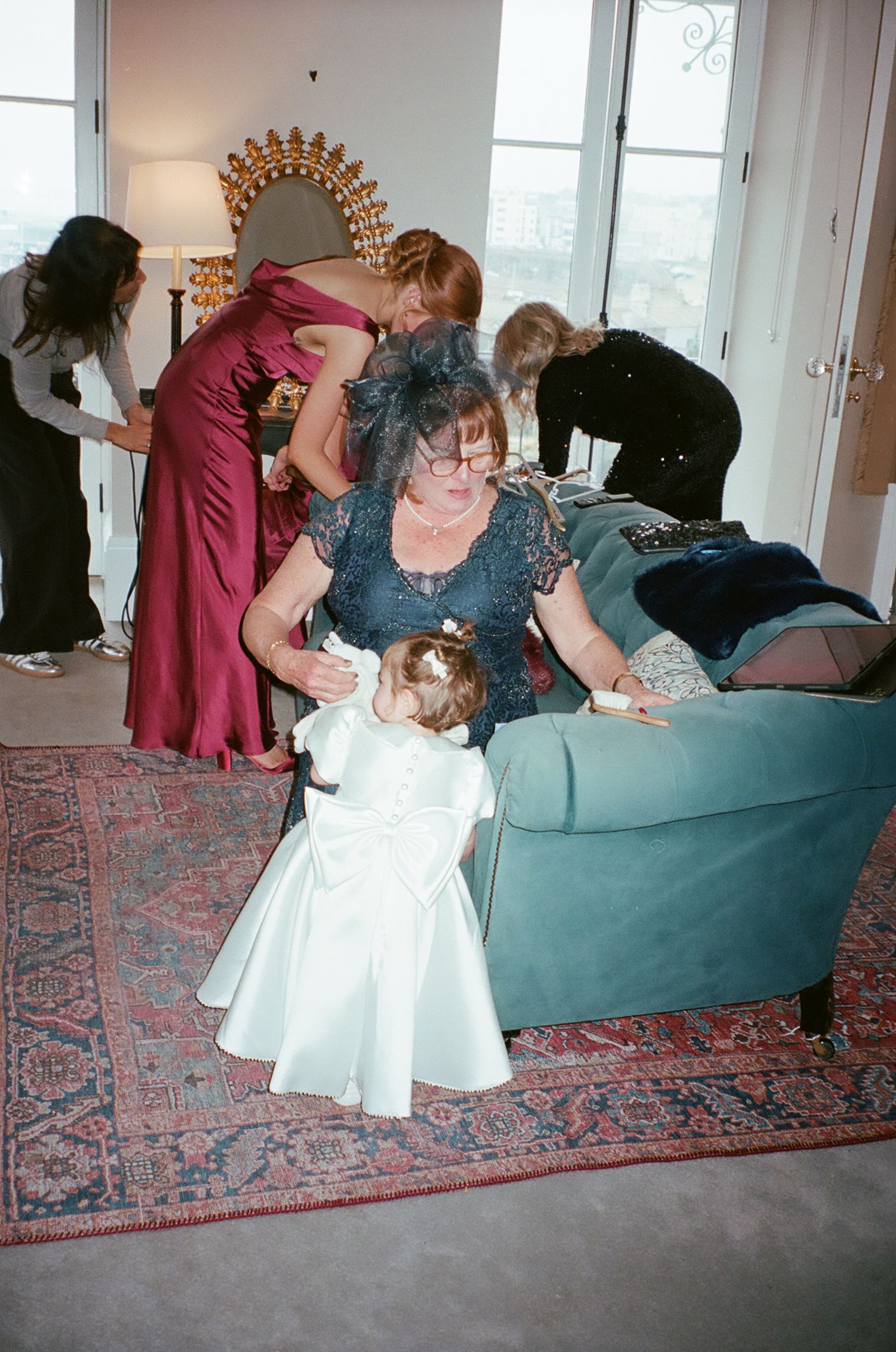 A series of photos showing someone in a burgundy dress helping adjust a white dress on a carpeted floor.