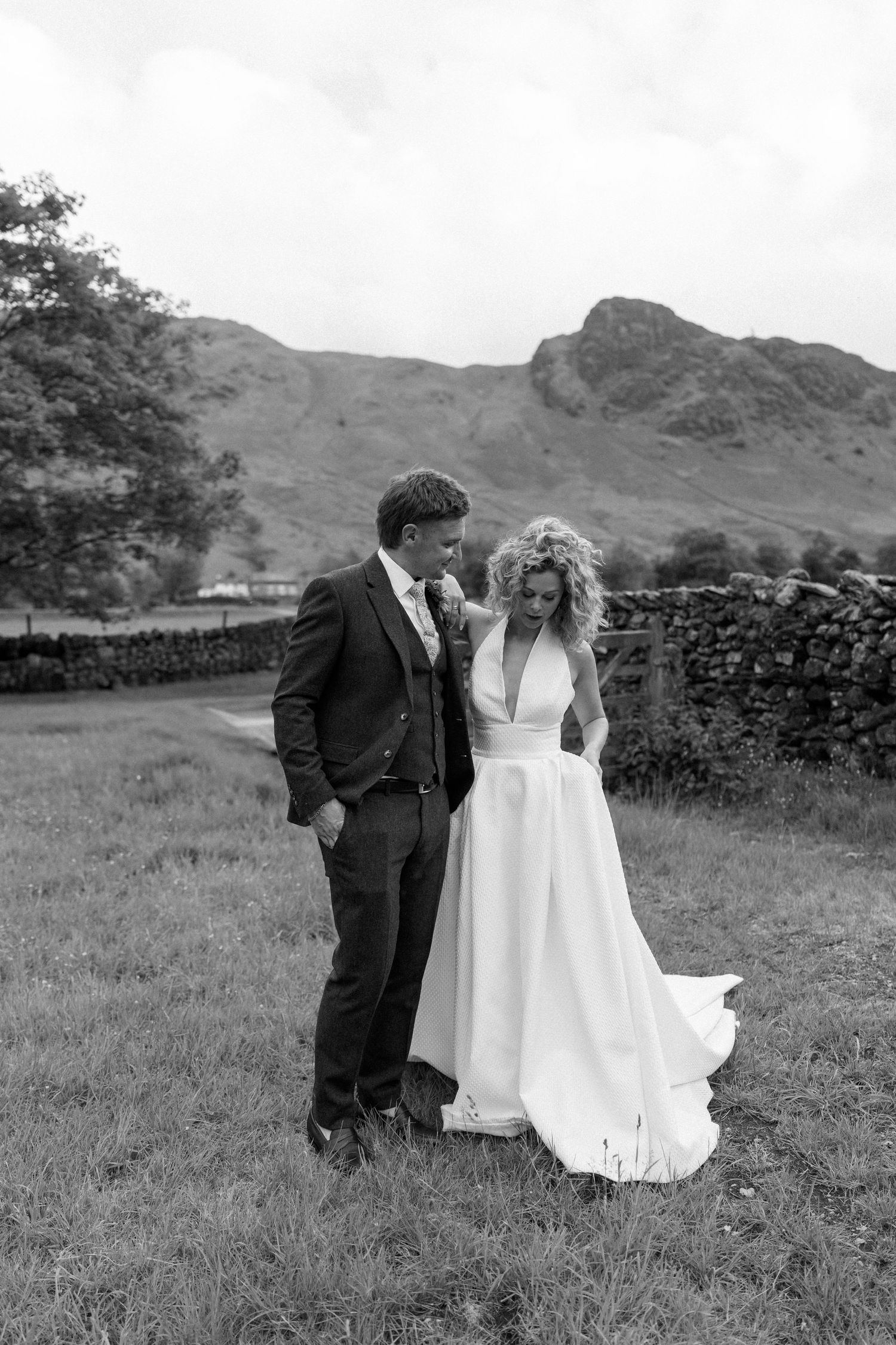Wedding couple posing in field with mountain landscape backdrop.
